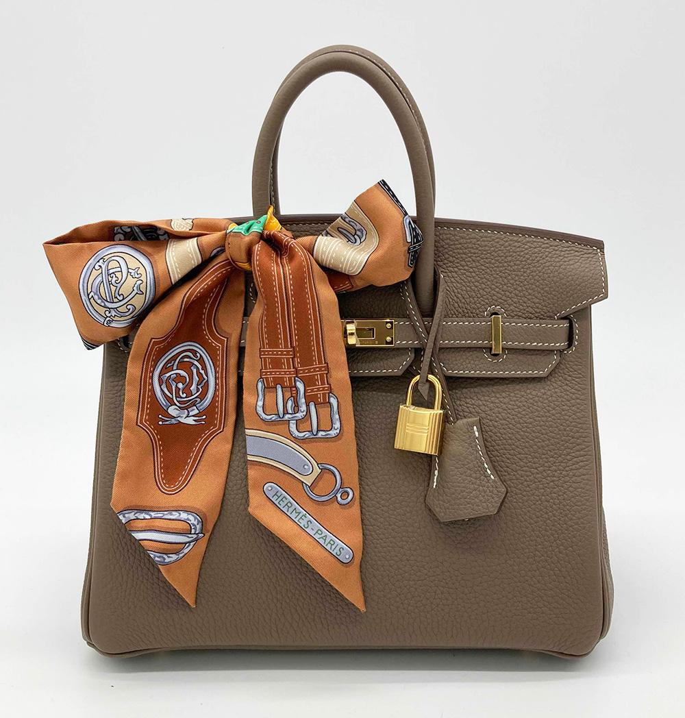 NWOT Hermes Etoupe Togo Birkin 25 GHW in mint unused condition. Etoupe togo leather exterior trimmed with gold hardware which still retains protective plastic covering. Signature birkin twist top flap closure opens to a matching kidskin lined