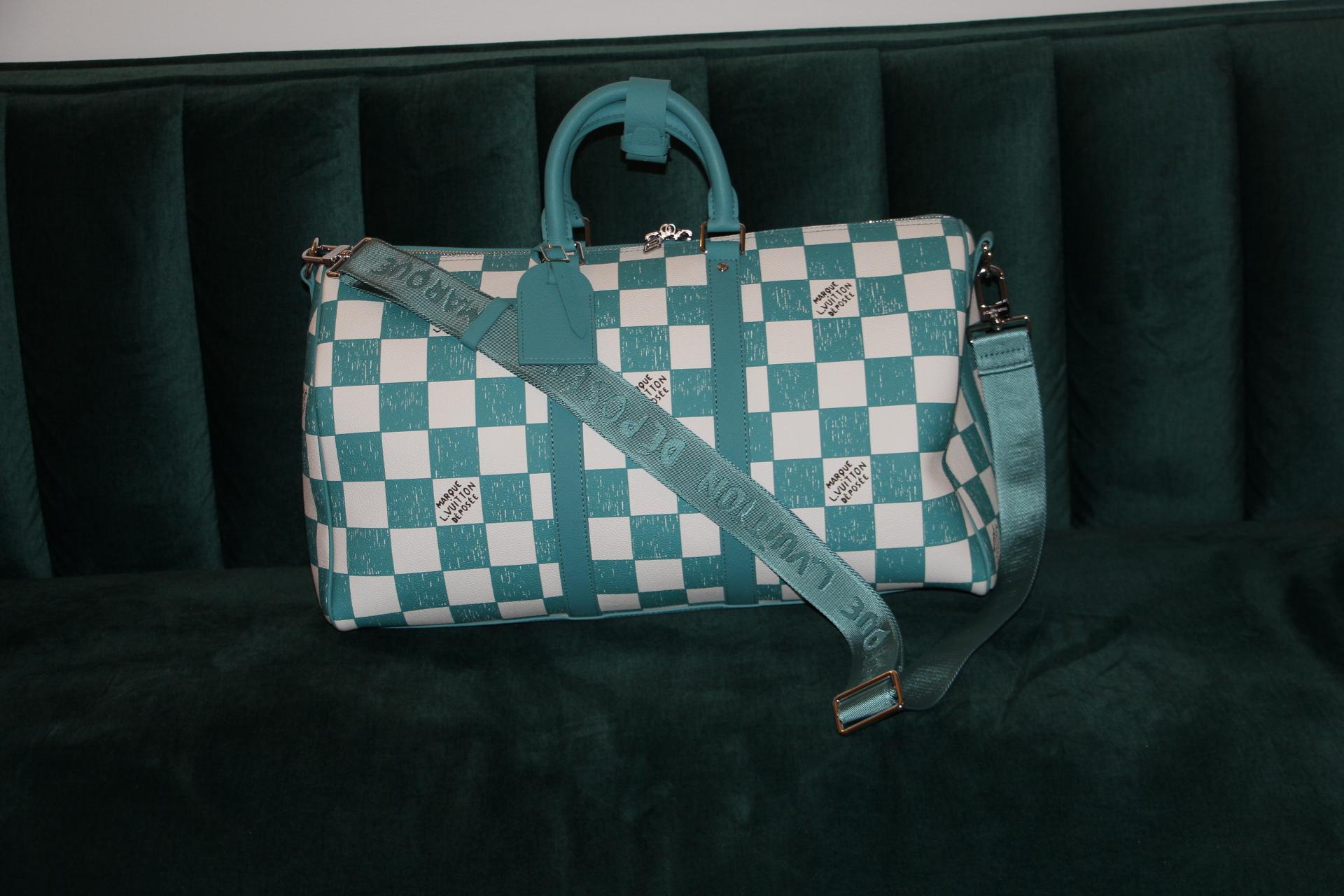 Ce superbe sac Keepall Bandoulière 45 est entièrement réalisé en cuir avec un motif damier Damier bleu turquoise et blanc. Ses poignées supérieures, ses bandes latérales et son porte-nom en cuir sont également de couleur sarcelle. Les carrés ont