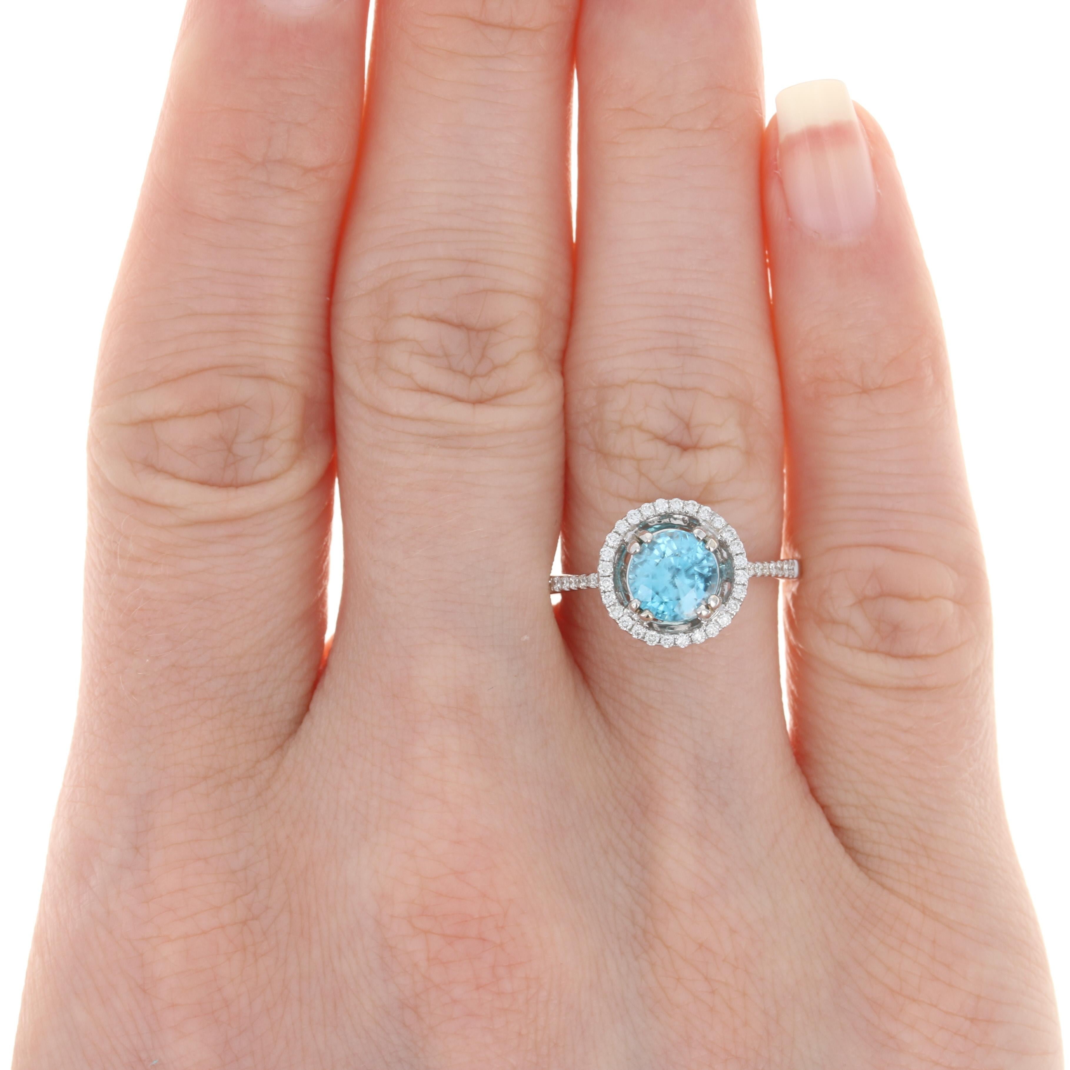 Your quest for the perfect birthday or anniversary gift ends here with this gorgeous ring! Fashioned in popular 14k white gold, this NEW piece features a blue zircon solitaire framed in a halo of sparkling diamonds. More diamond accents adorn