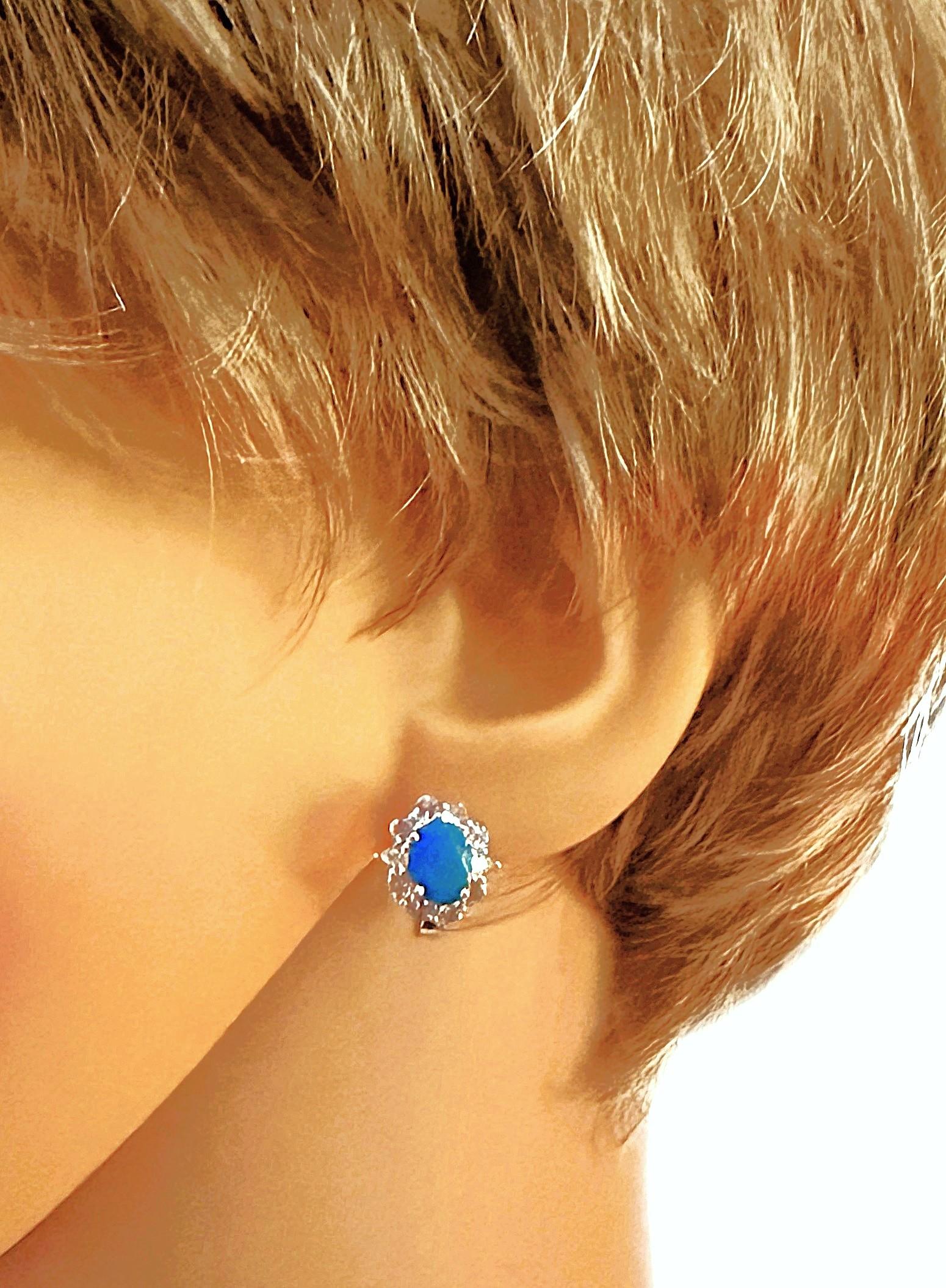 Diese Ohrringe sind einfach wunderschön!  Jeder Ohrring hat einen 8 x 6 mm großen äthiopischen blauen Opal im Ovalschliff.  Insgesamt sind es 2.42 Karat.  Sie sind von weißen, hellvioletten Tansaniten im Diamantschliff umgeben, und an den Seiten der