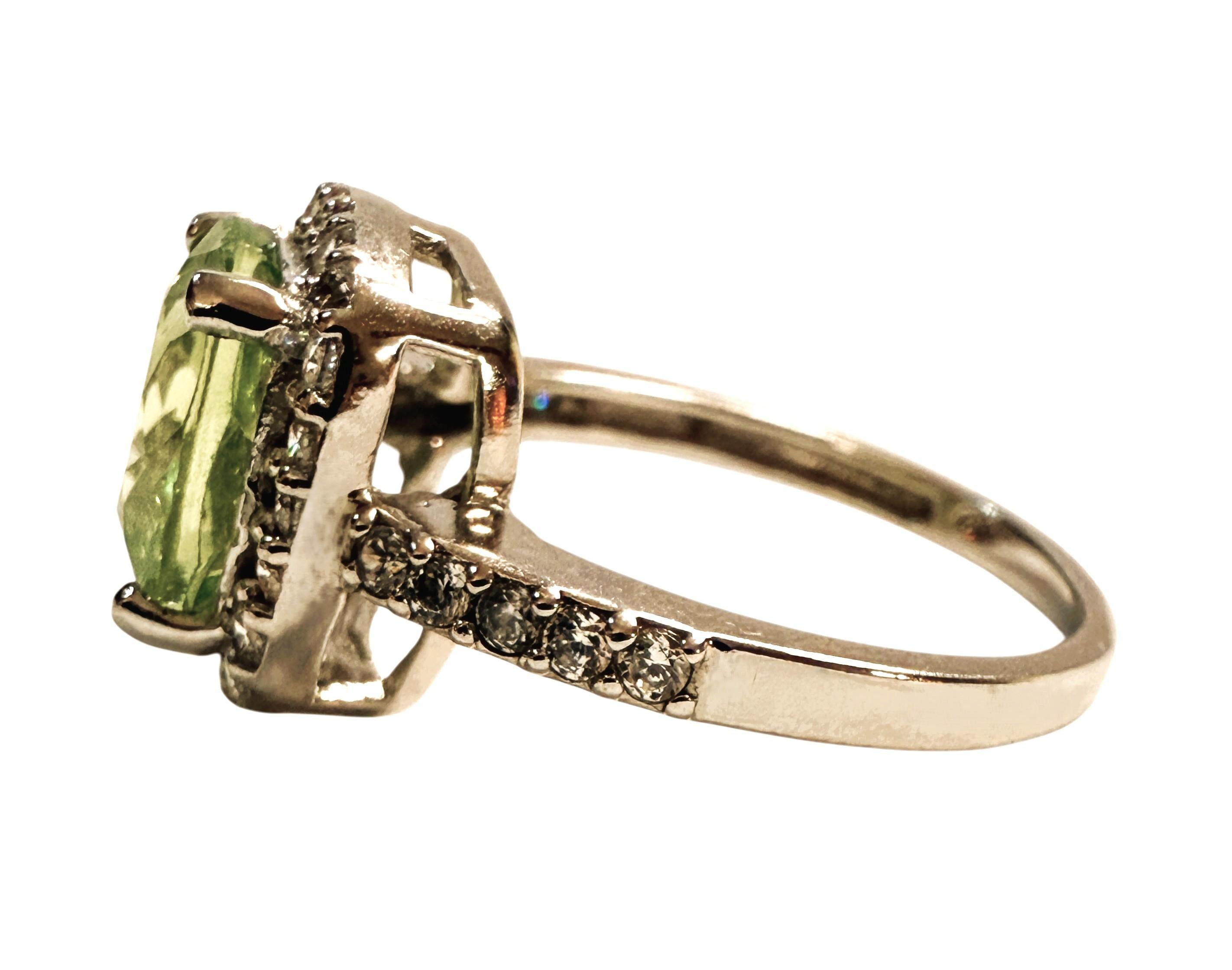 Der Ring hat die Größe 6,25. Dieser Stein stammt aus Afrika.  Es ist ein schöner Stein im Kissenschliff und hat 4 Karat.   Es misst 9,2 x 9,2 mm.  Der Stein ist von weißen Saphiren im Diamantschliff umgeben, die auch auf dem Band verlaufen.  Der