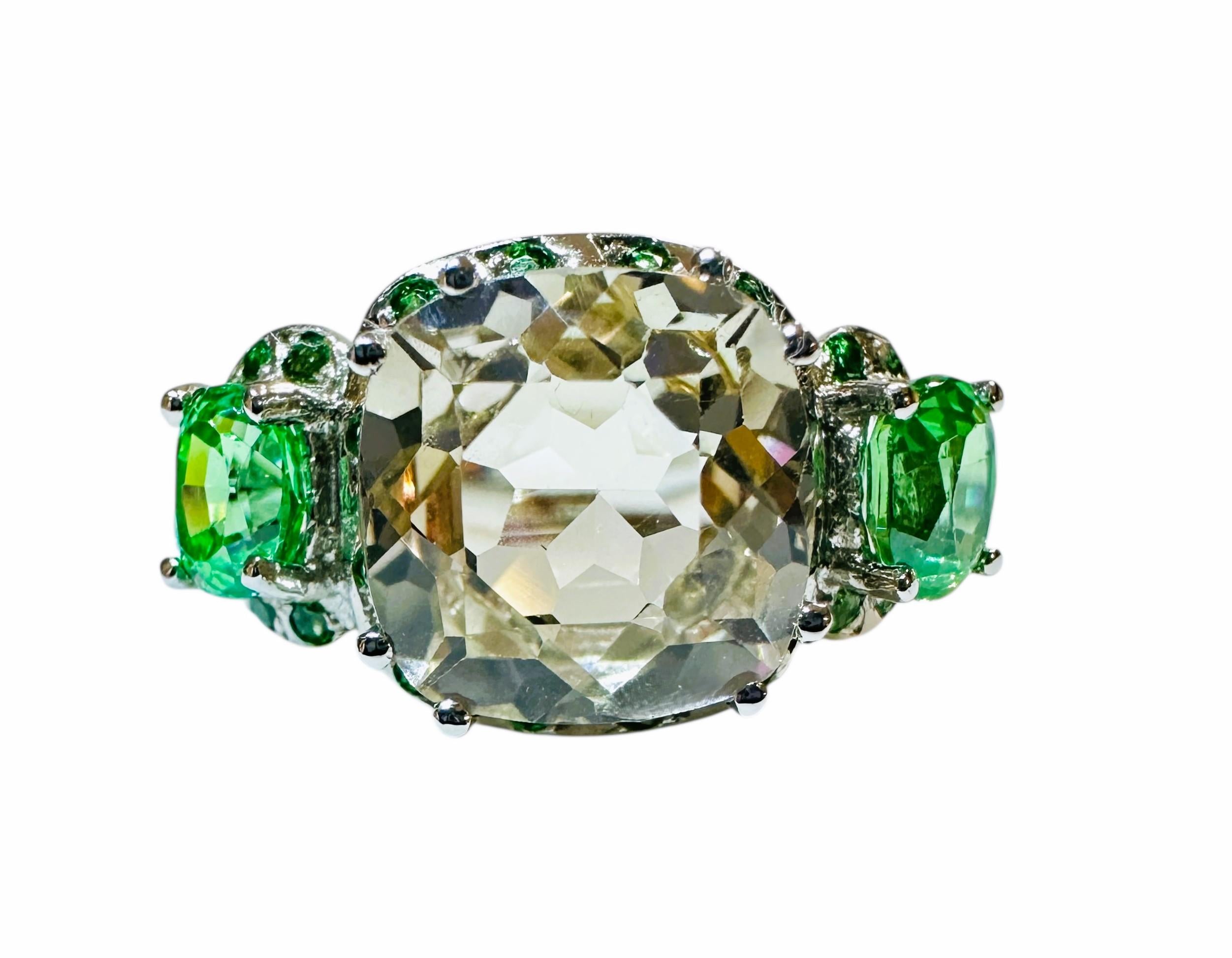 This is a very fetching ring.  This stone is from Sri Lanka and just a beautiful color of green.  The ring is a size 6.5.   It is a cushion cut stone and is 9.5 x 9.5 mm. It is surrounded by diamond cut Tsavorite Garnet stones and has an oval cut