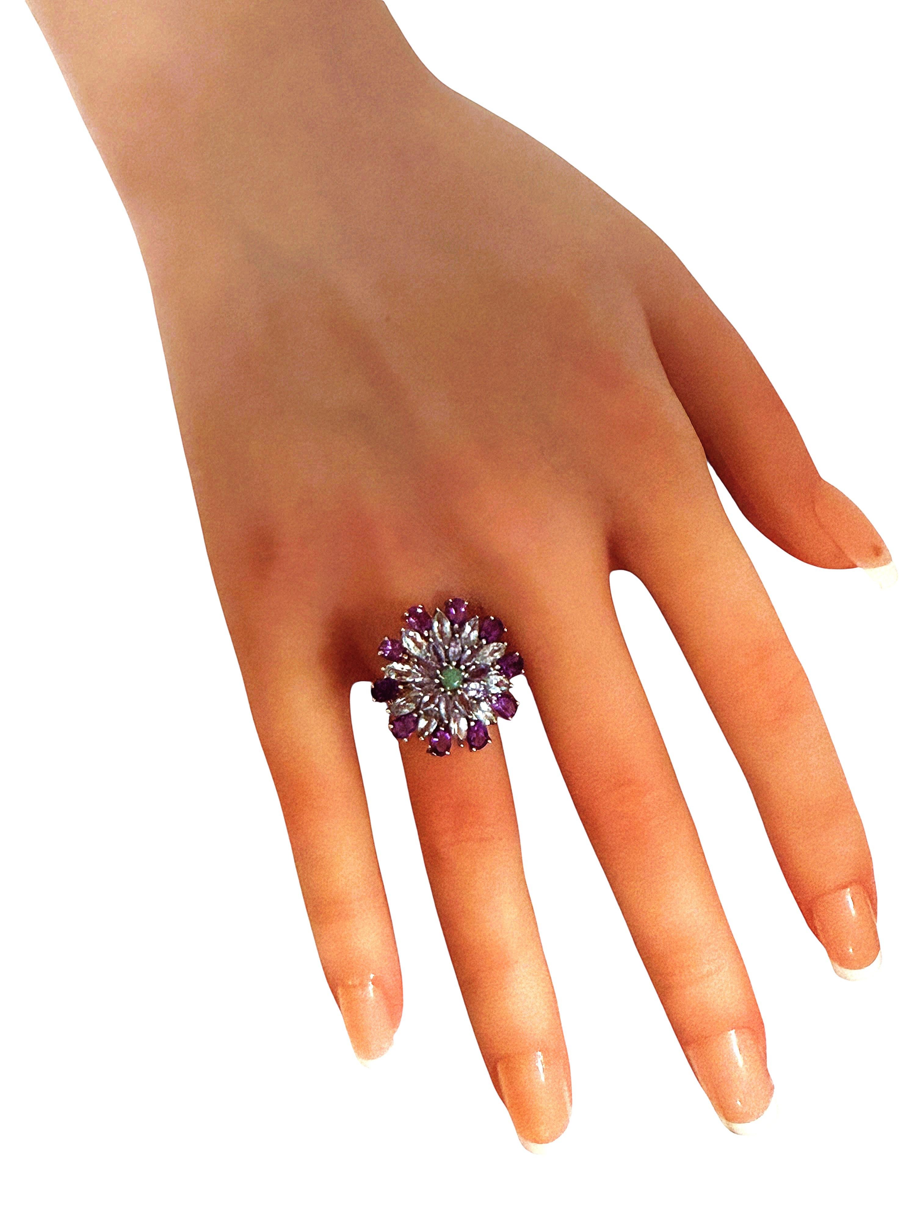 This is just a beautiful ring.  In the center is a 2.5 mm natural emerald totaling .06 carats.  Surrounding that is 10 marquise cut light purple sapphires totaling .9 carats.  Surrounding those are 10 mm marquise cut Aquamarine totaling 1.8 carats. 