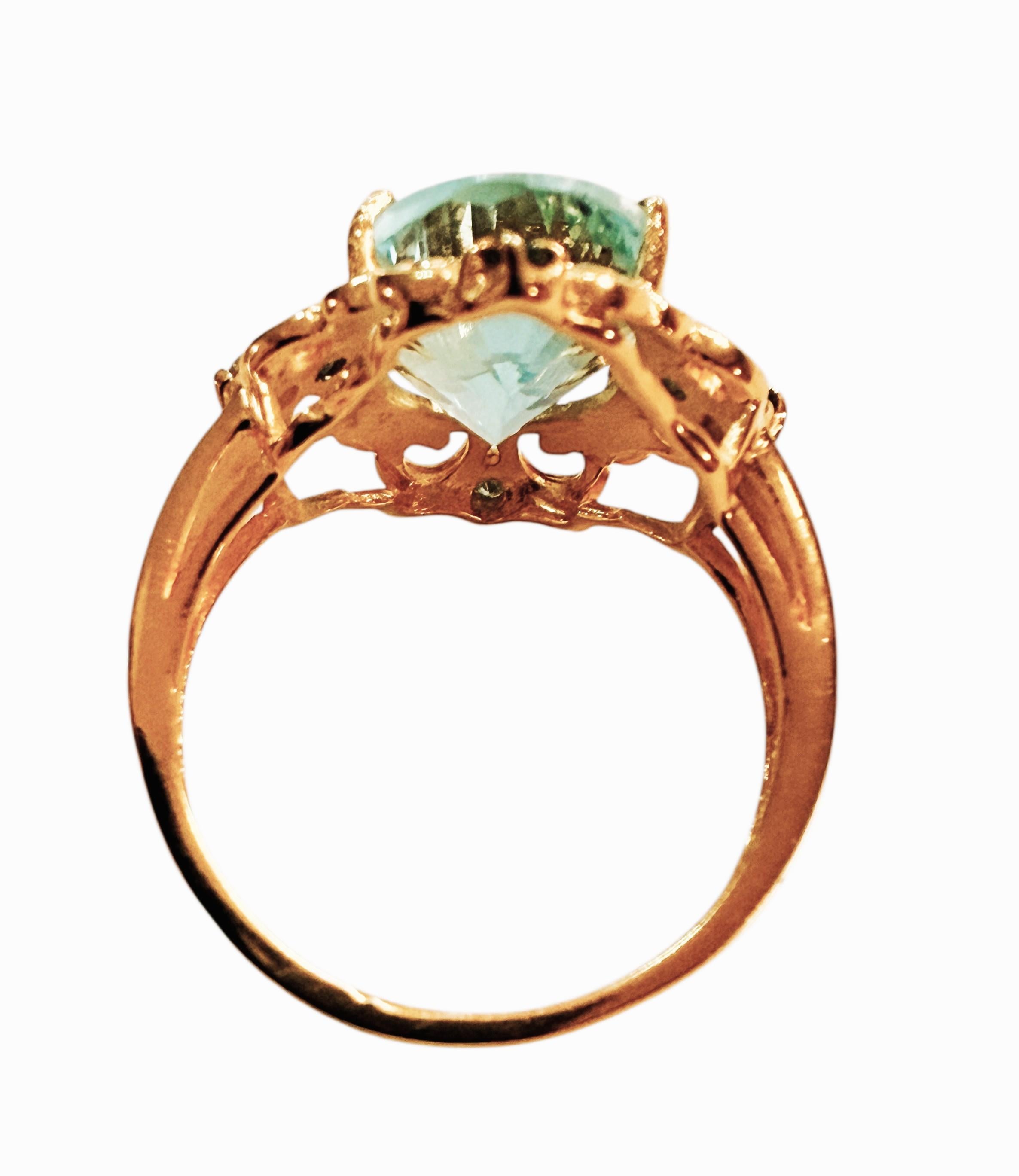 Es un anillo muy singular y bonito. La piedra es un Topacio Azul de talla Oval Cóncava y mide 5,81 quilates.  Mide 14 x 10 mm.  En las 4 esquinas hay piedras de topacio azul talla diamante de color azul más claro y más oscuro.  Están engastadas en