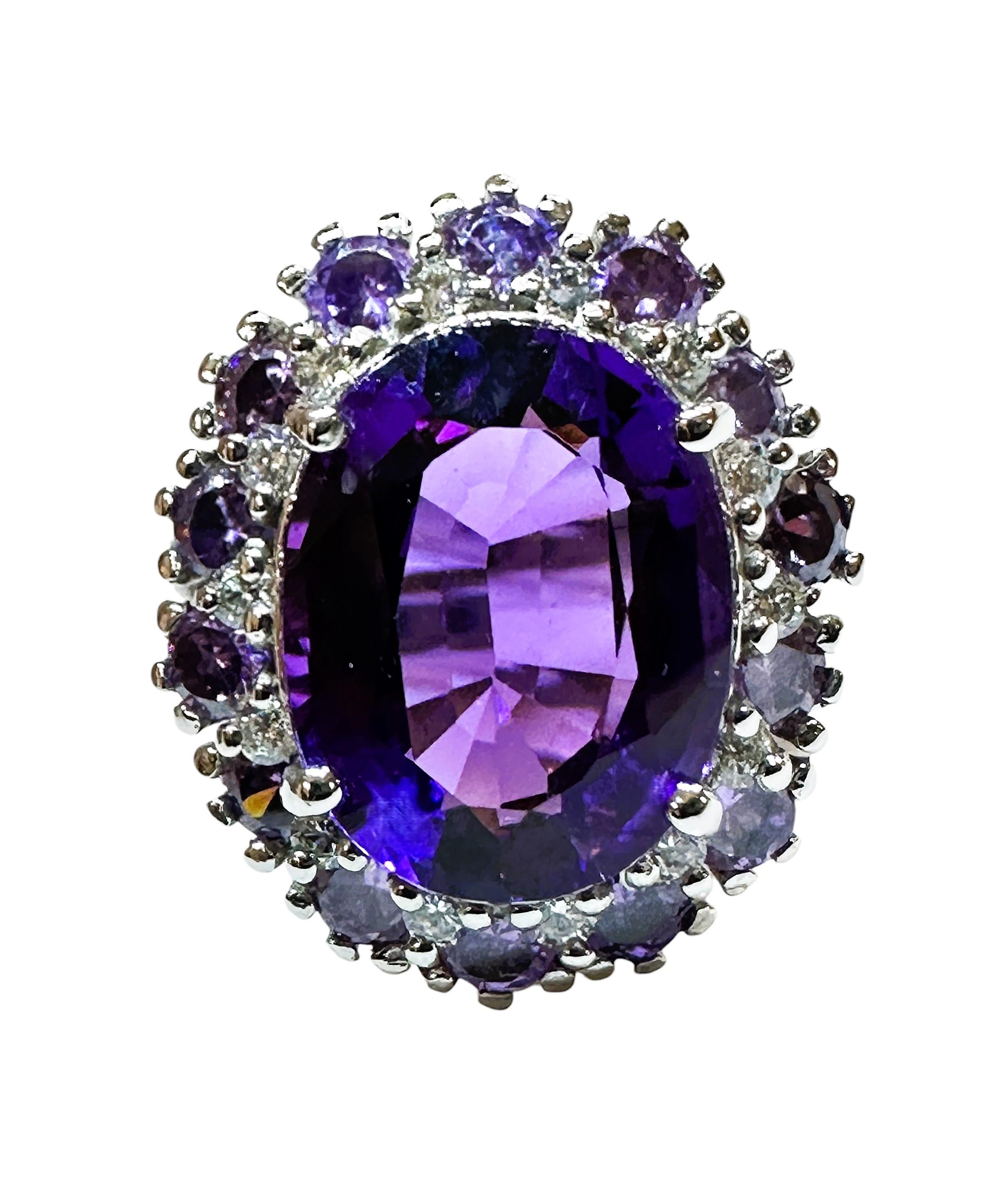 La piedra procede de Brasil y está bellamente tallada y es exquisita. Tiene una piedra Amatista de 7,0 quilates y mide 14 x 10,8 mm.  Está rodeada de zafiros blancos tallados con diamantes y éstos a su vez están rodeados de zafiros morados tallados