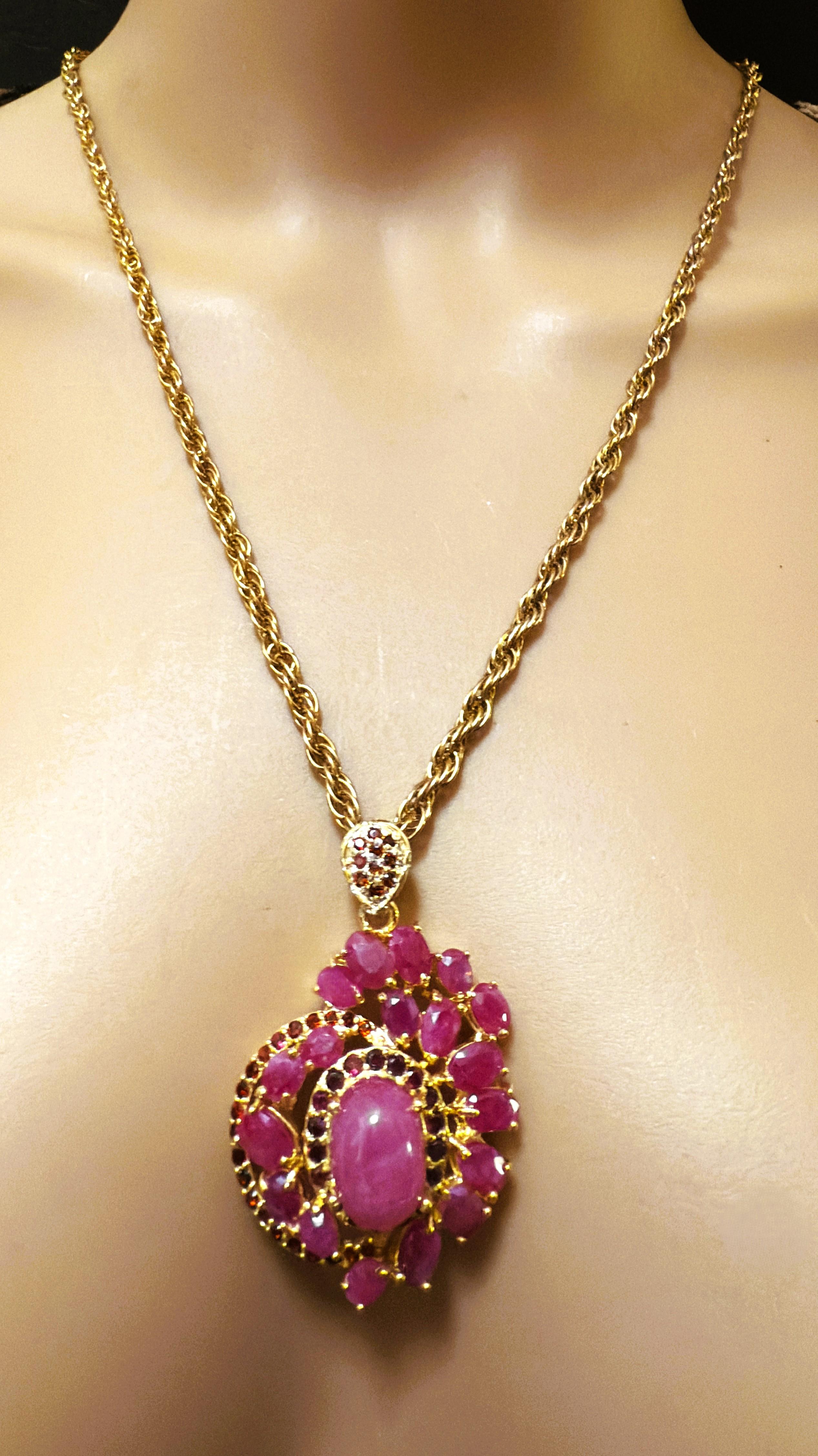 Este collar es precioso. Esta es una de esas piezas que me encantaría tener. Tiene una Piedra Central Cabujón de Rubí que mide 12 x 9,3 x 7 y es de 7,4 quilates sola.  Está rodeado de granates morados tallados con diamantes, que también están en el