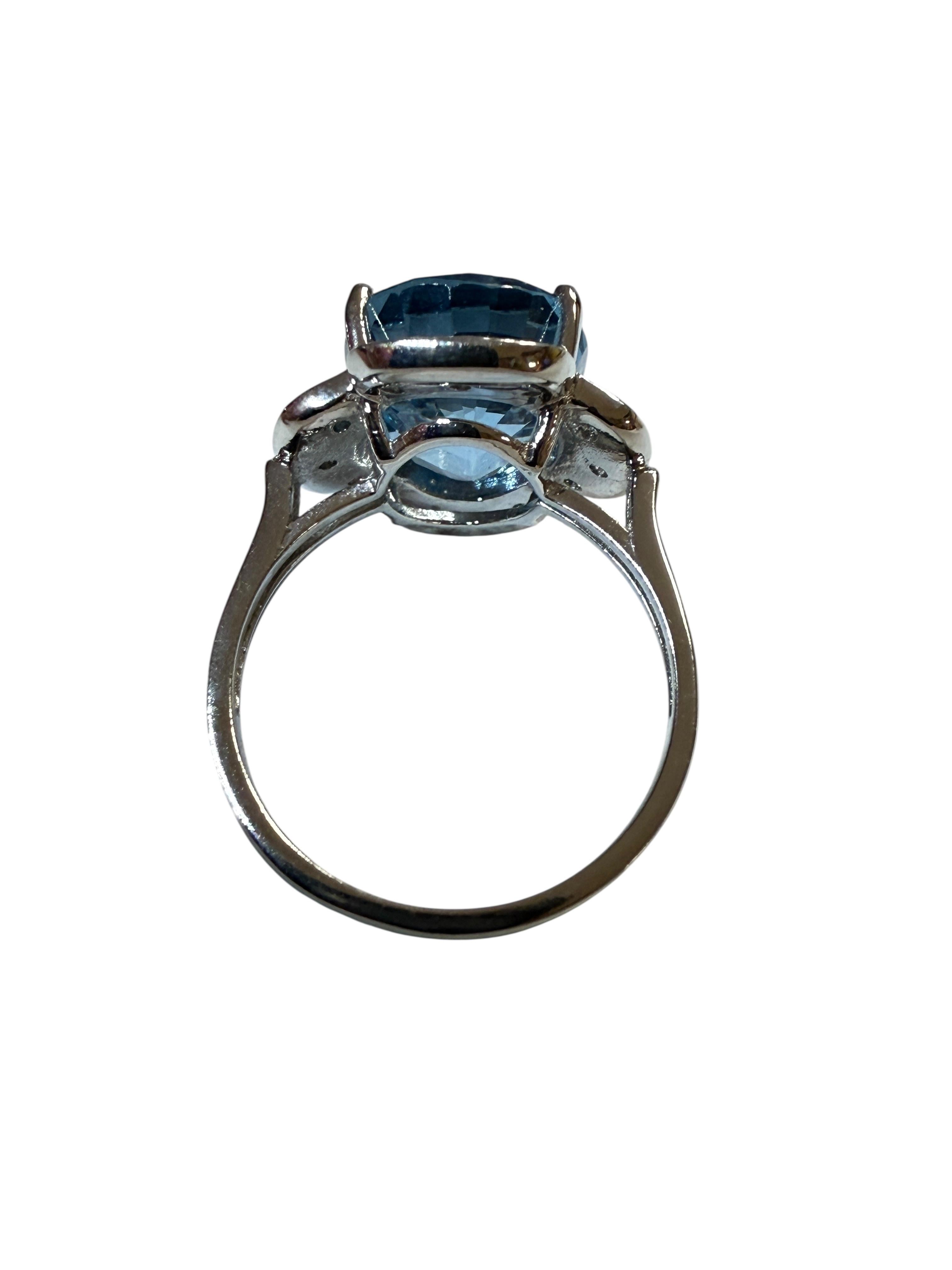 La piedra procede de África y es sencillamente exquisita. La piedra es un topacio azul de Londres y mide 7,90 quilates.  La piedra es de talla oval de fantasía, mide 12,8 x 10,7 mm y está rodeada de zafiros aguamarina talla diamante por los 4 lados.