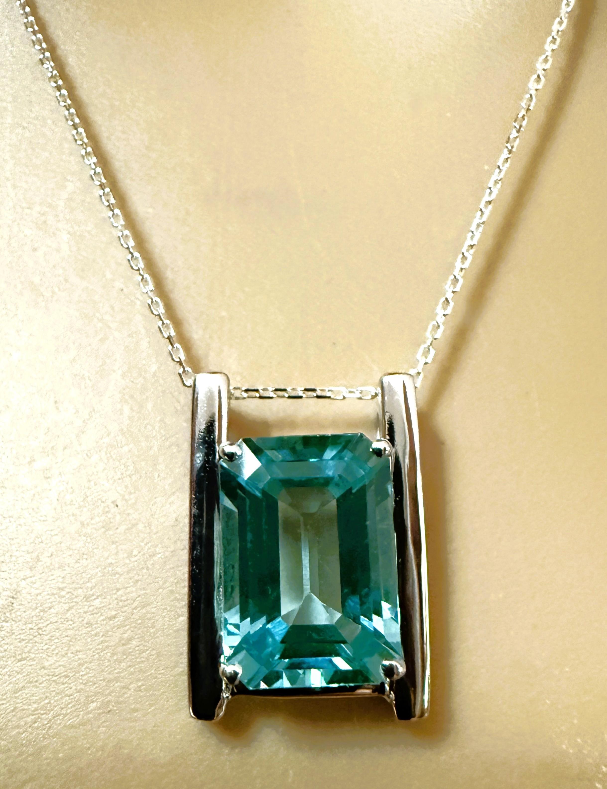 La pietra proviene dall'Africa ed è semplicemente squisita. La pietra è una tormalina Paraiba con taglio a smeraldo e misura 7,95 carati. Misura 14 x 10 mm.  Si tratta di un ciondolo solitario inserito in una modernissima montatura in argento