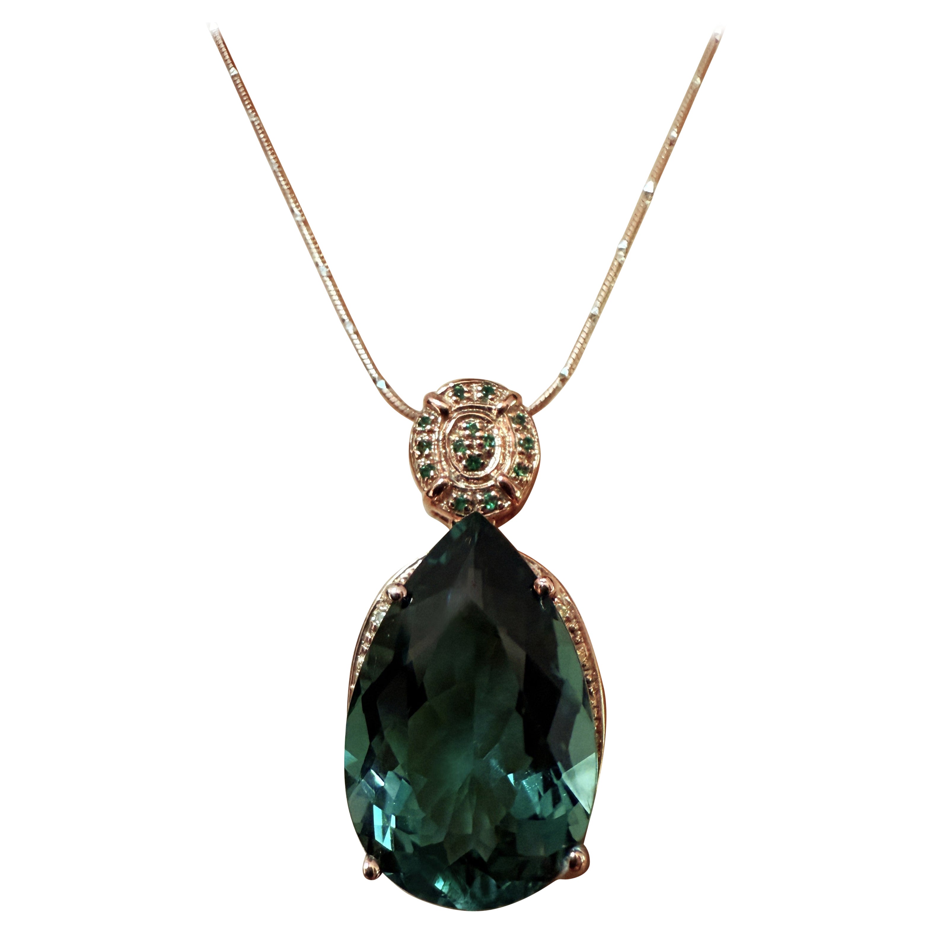 The stone is from Africa and is just exquisite. The stone is a pear cut Teal Green Tourmaline and is 9.70 carats. It measures 14 x 10 mm.  It is surrounded by diamond cut white sapphires and bail is encrusted with diamond cut green sapphires.  They