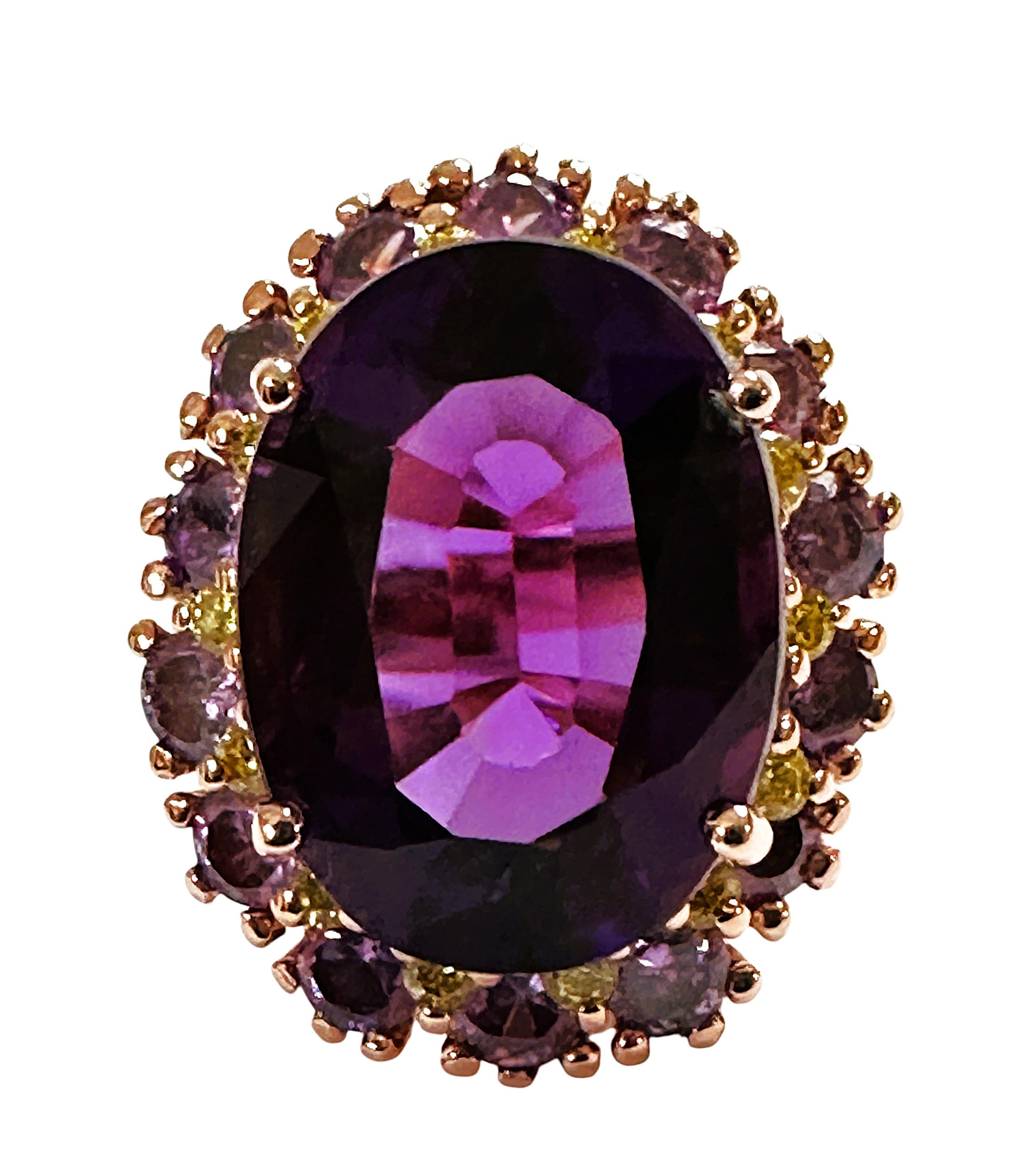 La piedra procede de Brasil y está bellamente tallada y es exquisita. Es una piedra Amatista de 9,70 quilates y mide 16 x 11,8 mm.  Está rodeada de zafiros blancos tallados con diamantes y éstos a su vez están rodeados de zafiros morados tallados