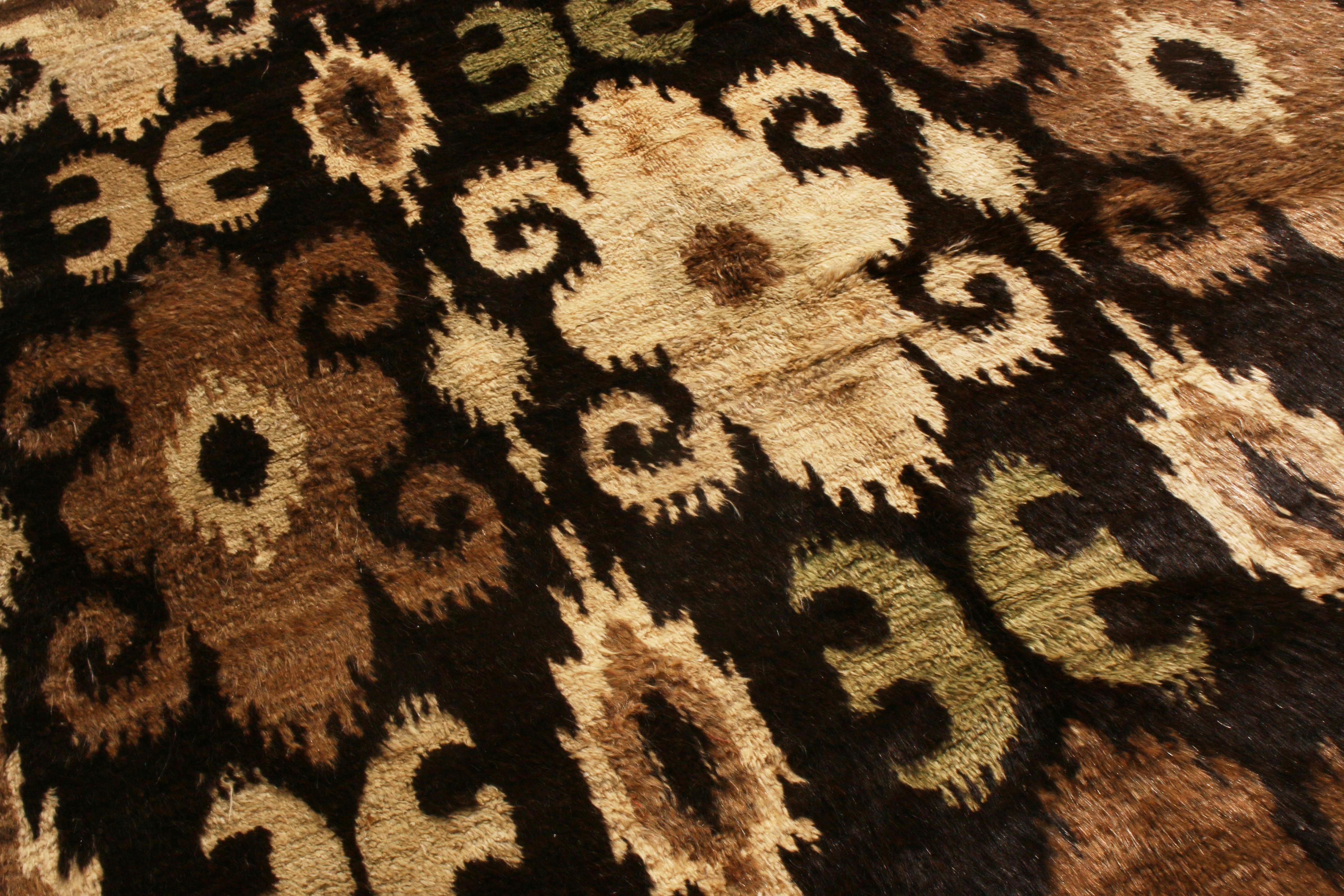 Originating from Afghanistan, this new Aghan wool rug is hand knotted in thick, high quality wool pile with a smoothness like that of goat hair. A deep black background within a rich brown wrapping guard border is complemented by beige, chestnut