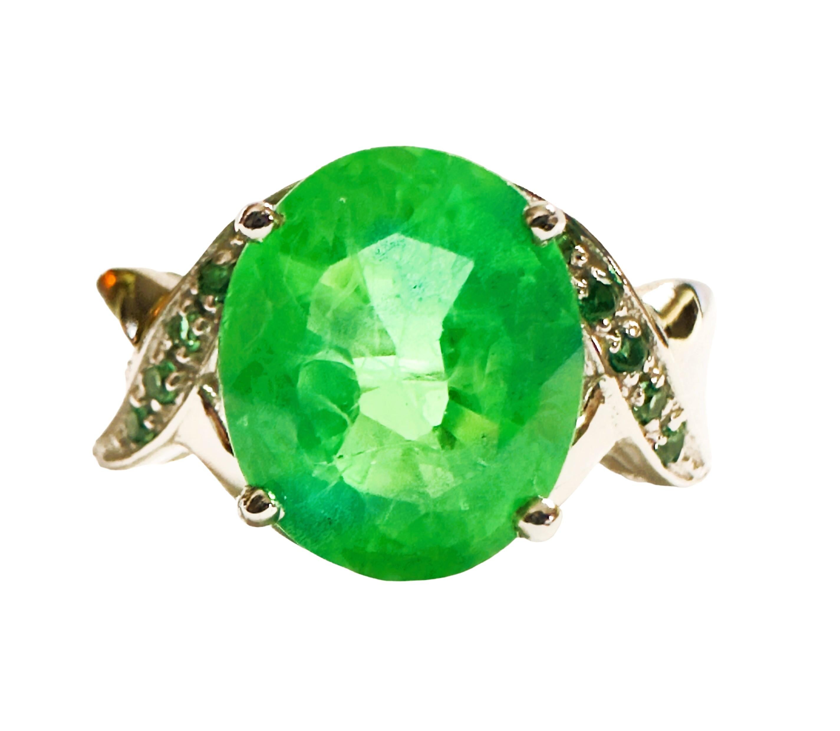 What beautifully constructed ring.  The ring is a size 6.5.   The stone is from Africa and is just exquisite.  It is a highly rated stone.  It is an oval cut stone and is 5 Cts   The main stone is 10.3 x 8.7 mm and is flanked by Diamond Cut Green