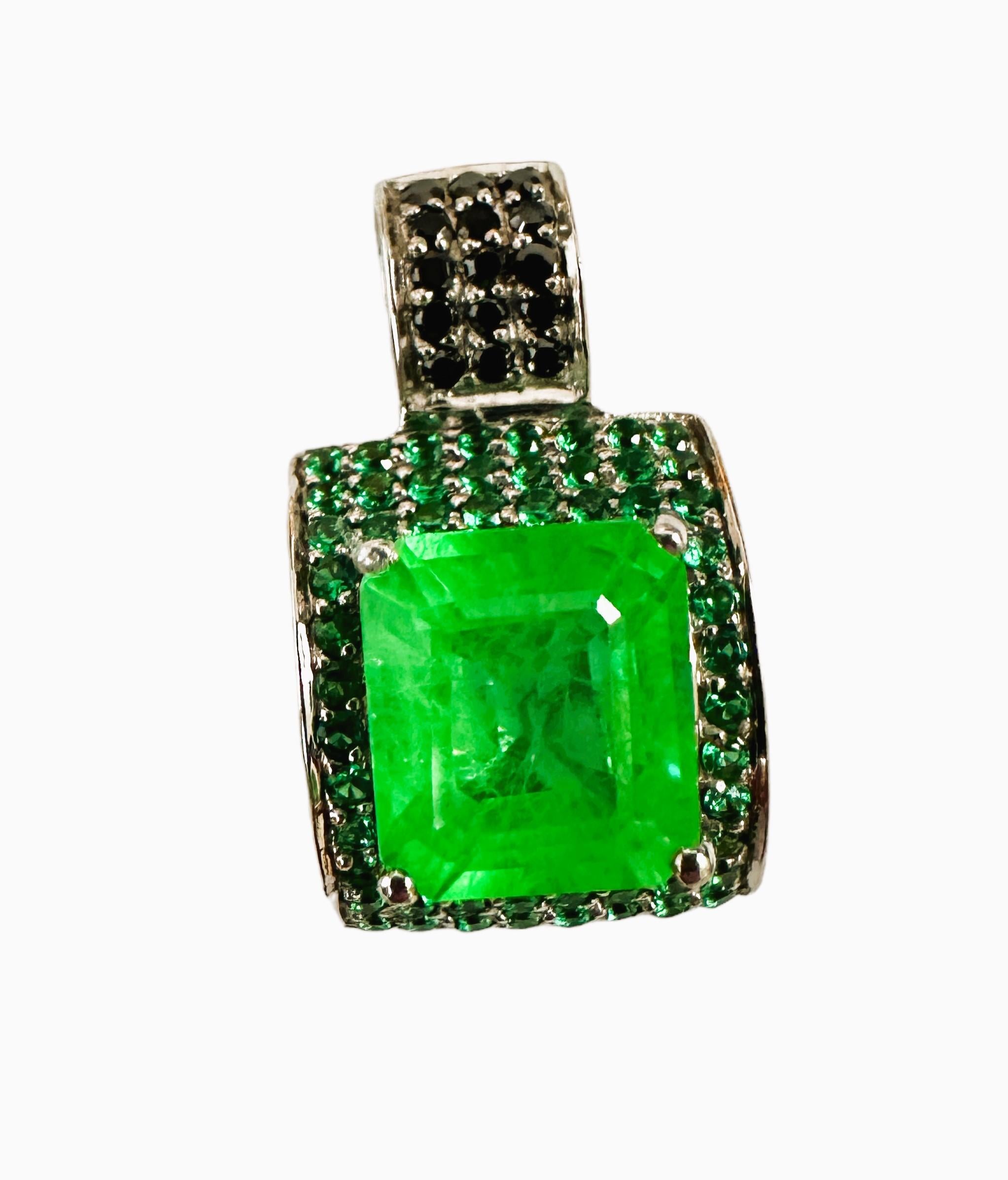The is a beautiful pendant with an 8 ct Green Garnet Sapphire that is 8 carats and measures 11.3 mm.  It is surrounded by diamond cut Green Tsavorite stones and the bail has diamond cut black spinel stones.  It measures  1 inch long and .68 inches