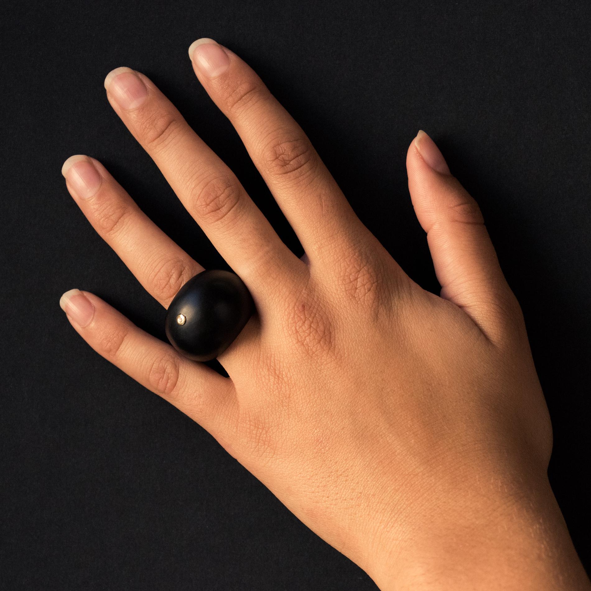 Ring in ebony.
This ball-shaped ring is adorned on its top with a diamond set with yellow gold.
Total weight of diamond: 0.016 carat approximately.
Height: 22.2 mm, width: 25 mm, thickness: 9.7 mm, width of the ring at the base: 11.5 mm.
Total