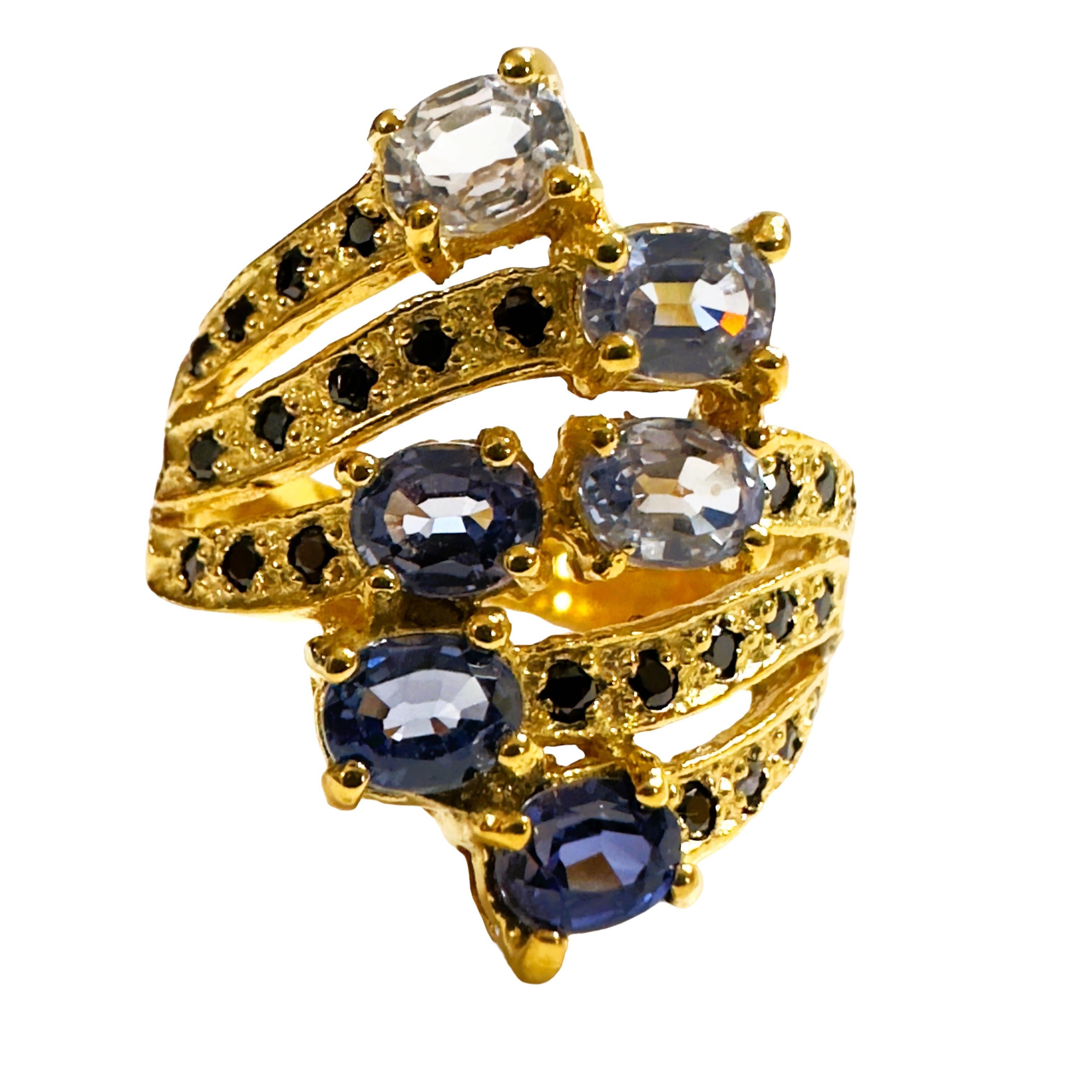 What a beautiful ring!  It has 6 oval Cornflower Sapphires in varying degrees of color. and also has diamond cut Black Spinels swirled around the band. 
 The ring is a size 8.  The stones are from Africa and are just exquisite.  The 
