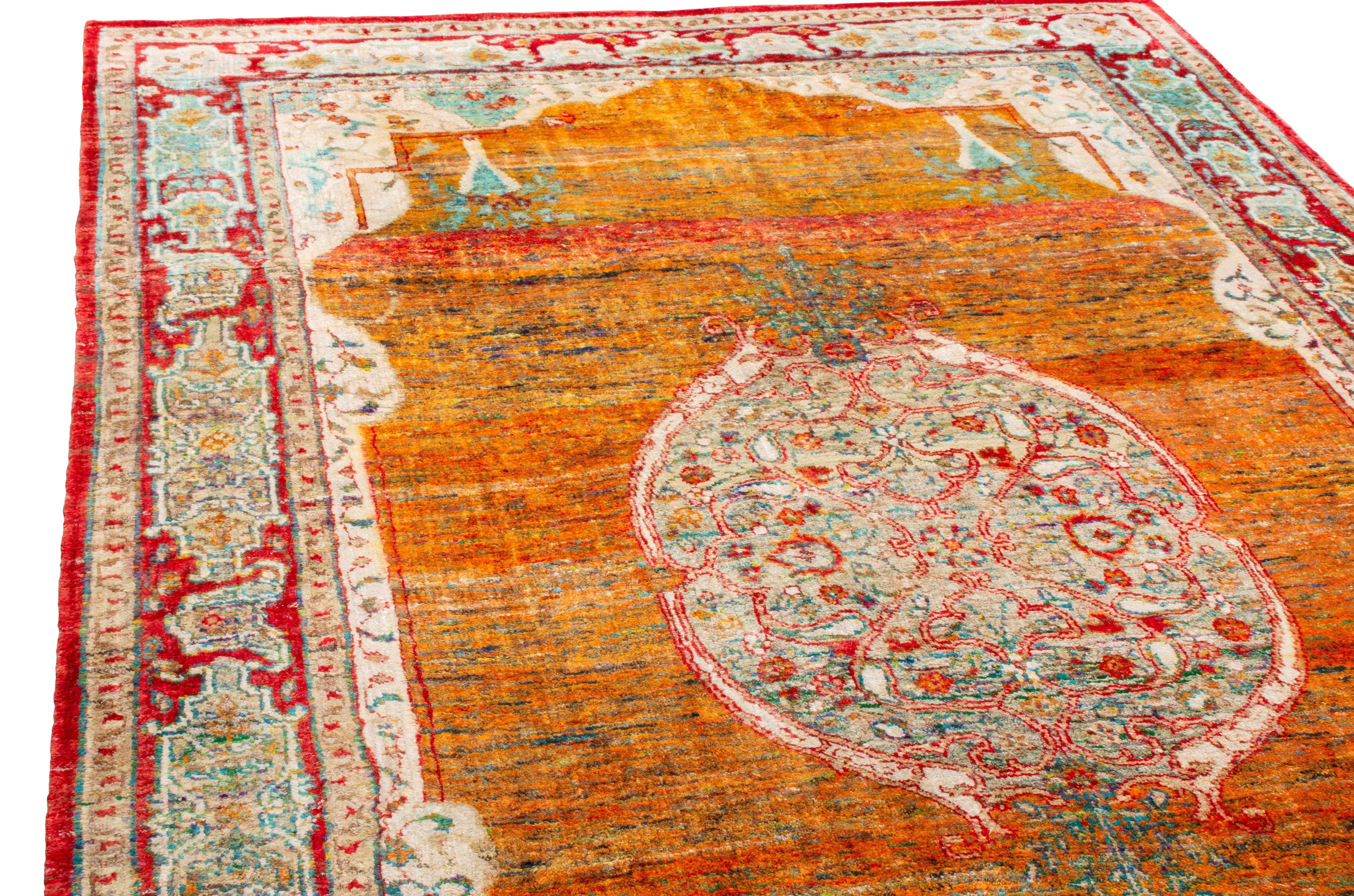 Originating from India, this new silk rug enjoys a tastefully unique background with an homage to an antique medallion field design. Hand knotted in lustrous, complementary silk, the abrash lengths of sunset orange, tangerine red, and cream yellow
