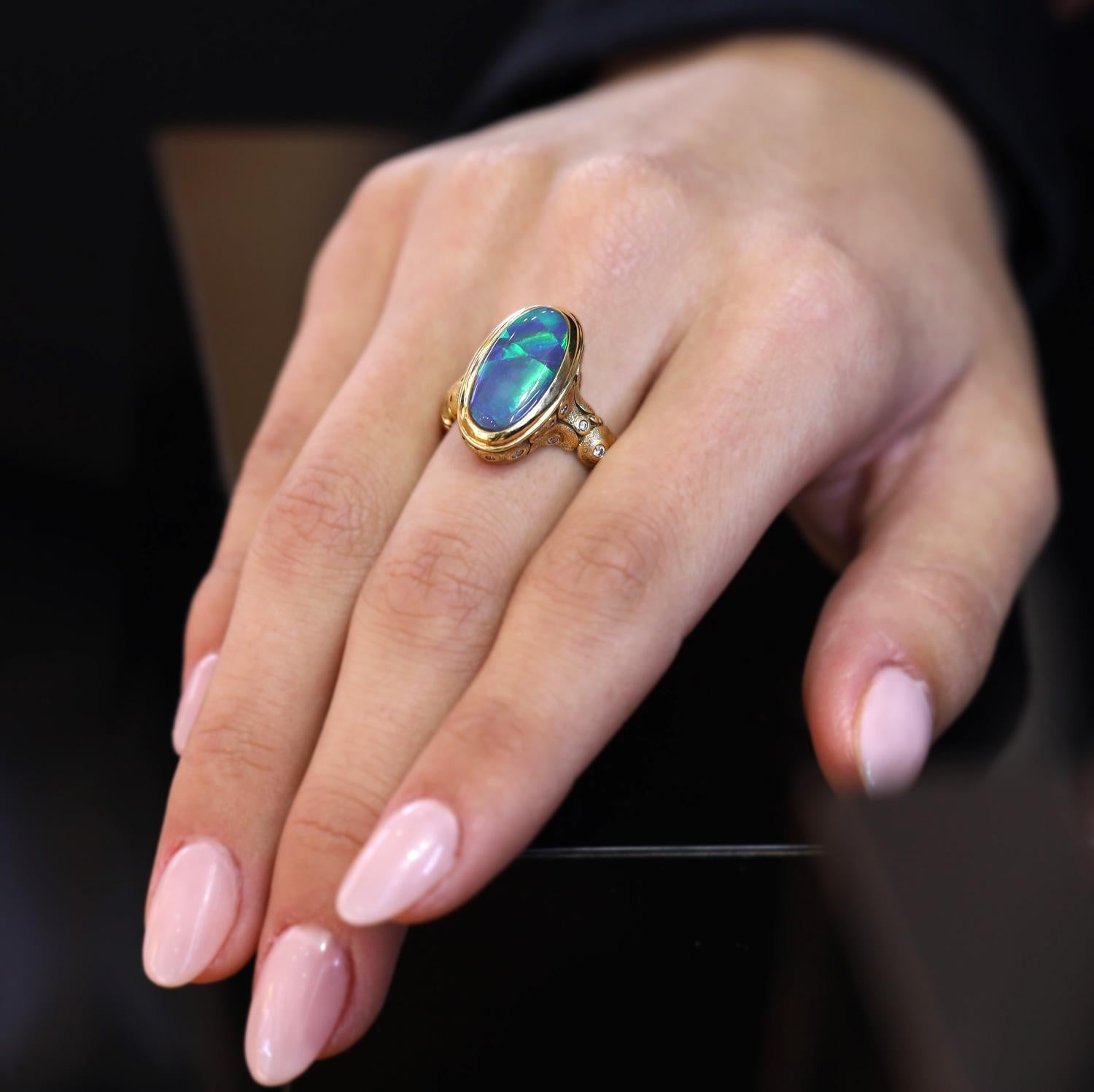 From noted New York City jewelry designer Alex Sepkus, this bespoke black opal ring is truly a work of art. The 4 carat opal displaying a fiery play of color exhibiting blue and green flashes is set in an organic, cobblestoned 18k yellow gold
