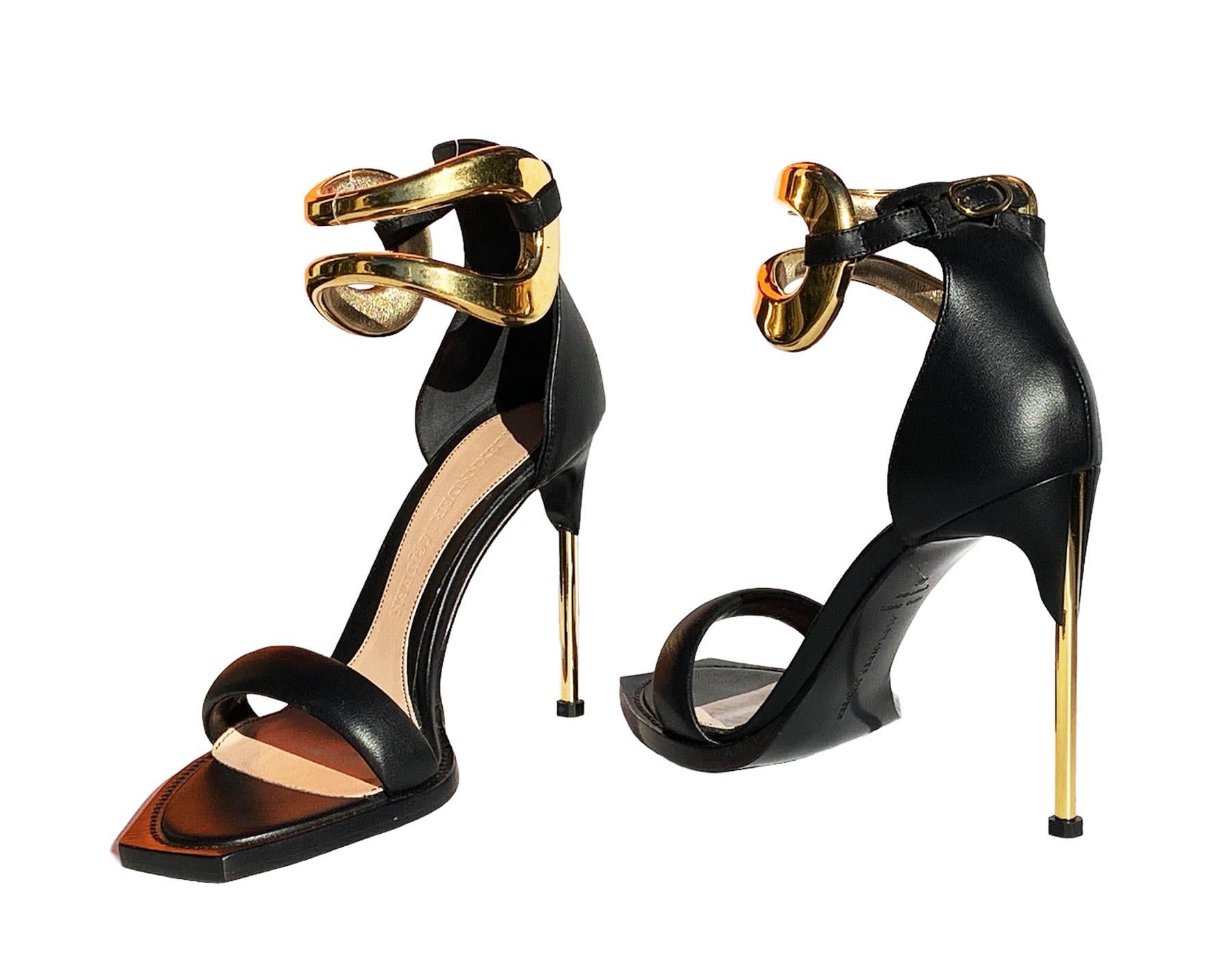 New Alexander McQueen Black Leather Ankle Wrap Sandals
Italian size - 40
Black Leather, Gold Tone Metal Ankle Strap with Buckle Closure, 
Square Toe, Gold Tone Metal Stiletto High Heel - 4.5 inches.
Leather Insole and Rubber/Leather Sole.
Made in