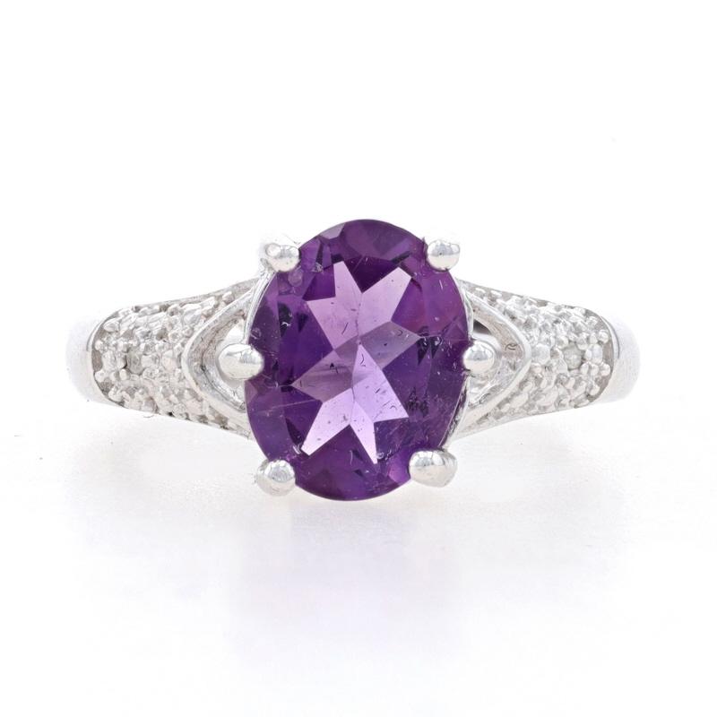 This beautiful NEW ring is sure to please! The ring is set with a 2.28 carat, oval cut genuine amethyst which is displayed in a six pronged setting. Two small single cut natural diamonds are set among the bead accenting to either side of the band.