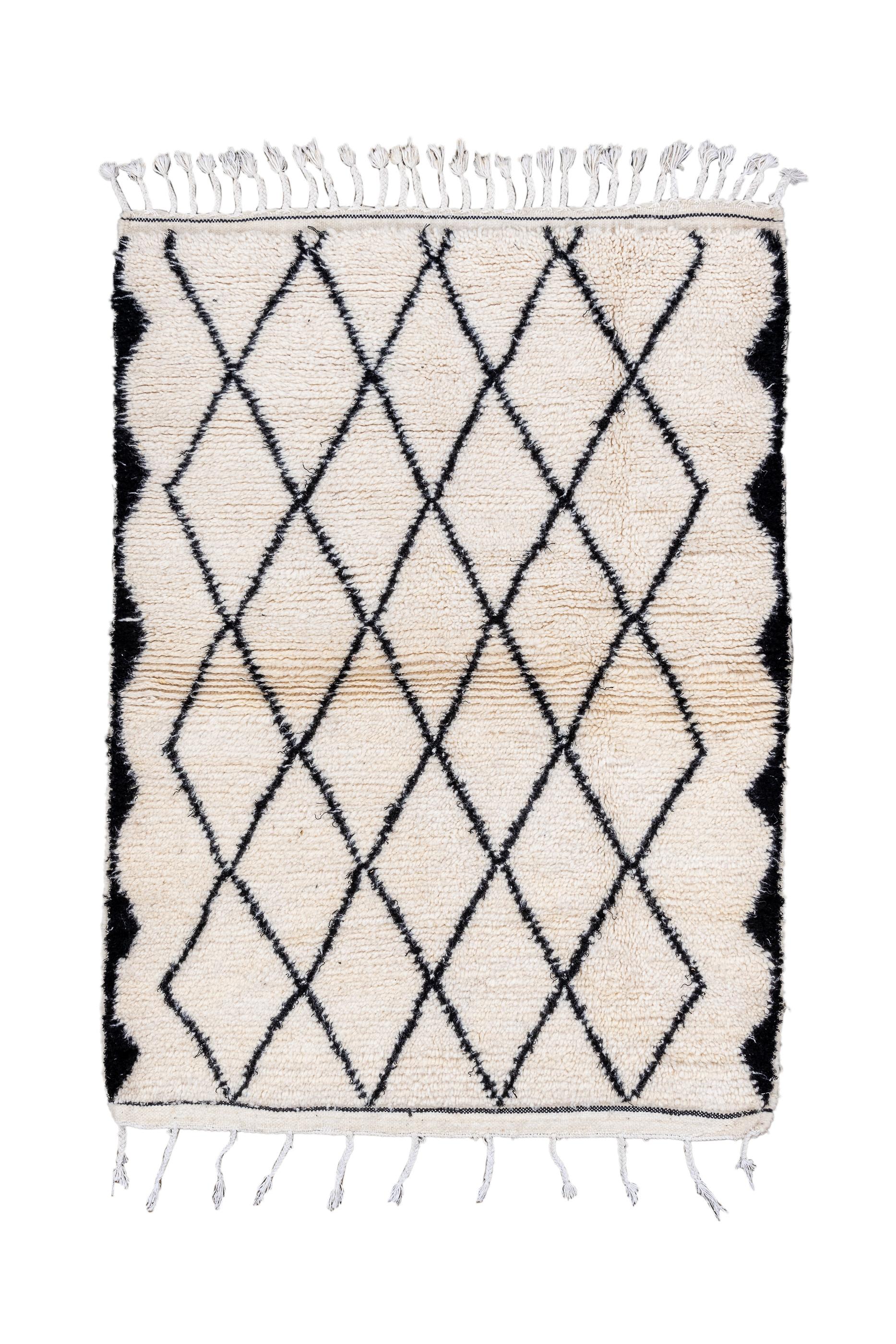 Marokkanische Weber lieben Rauten, wie hier mit einem durchgehenden Holzkohlegitter auf cremefarbener Naturwolle gezeigt. Die seitliche Umrandung aus Holzkohle besteht aus abgeflachten, unregelmäßigen Dreieckslinien. Weit auseinander liegende