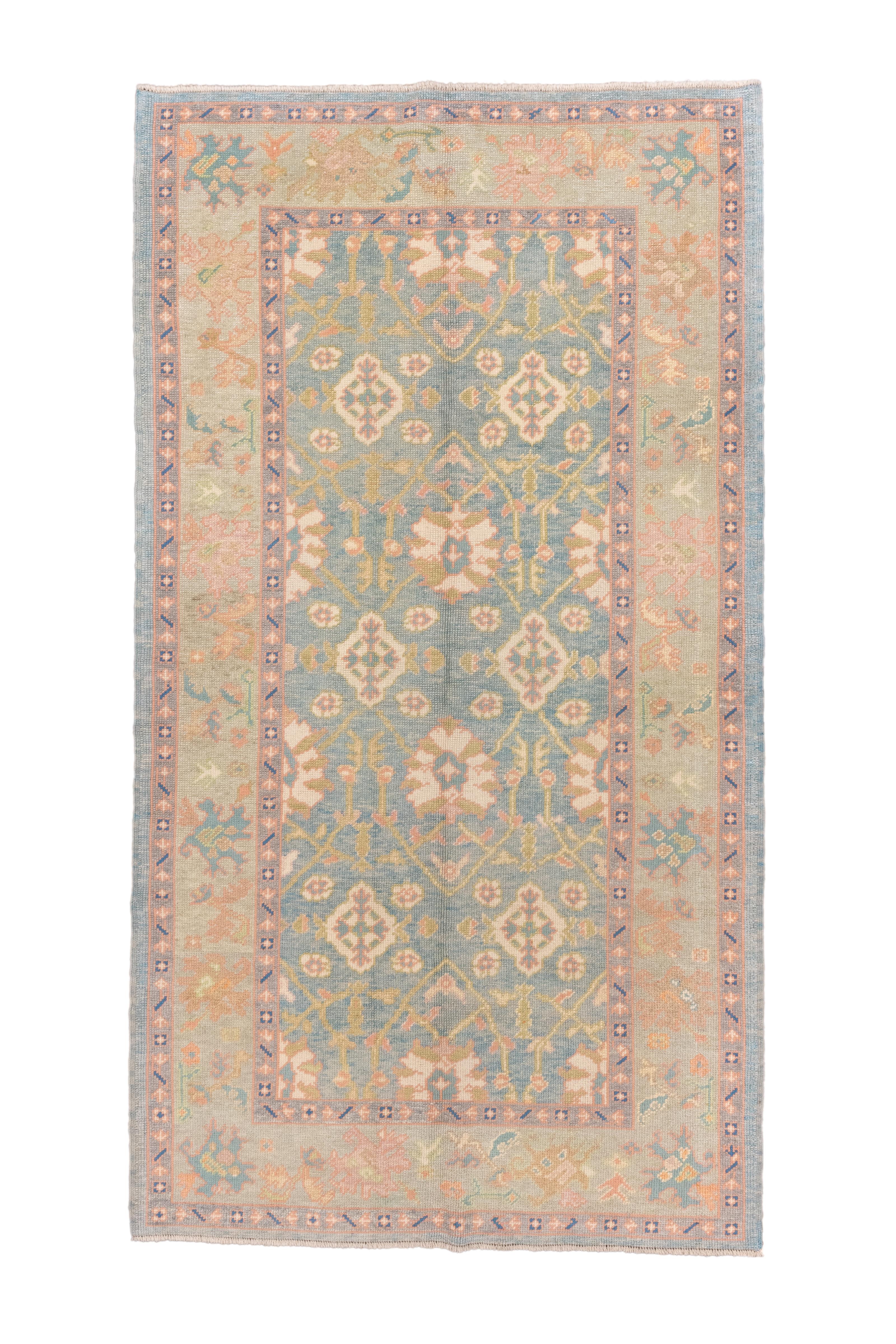 Das hellblaue Feld zeigt ein aufsteigendes, unidirektionales Muster aus bitonalen ovalen Palmetten in einem breiten Gitter aus schlanken, steifen Ranken.  Ecru-Kartuschen verstärken den Musterfluss. Beigefarbene Strohborte mit zerrissenen Palmetten,