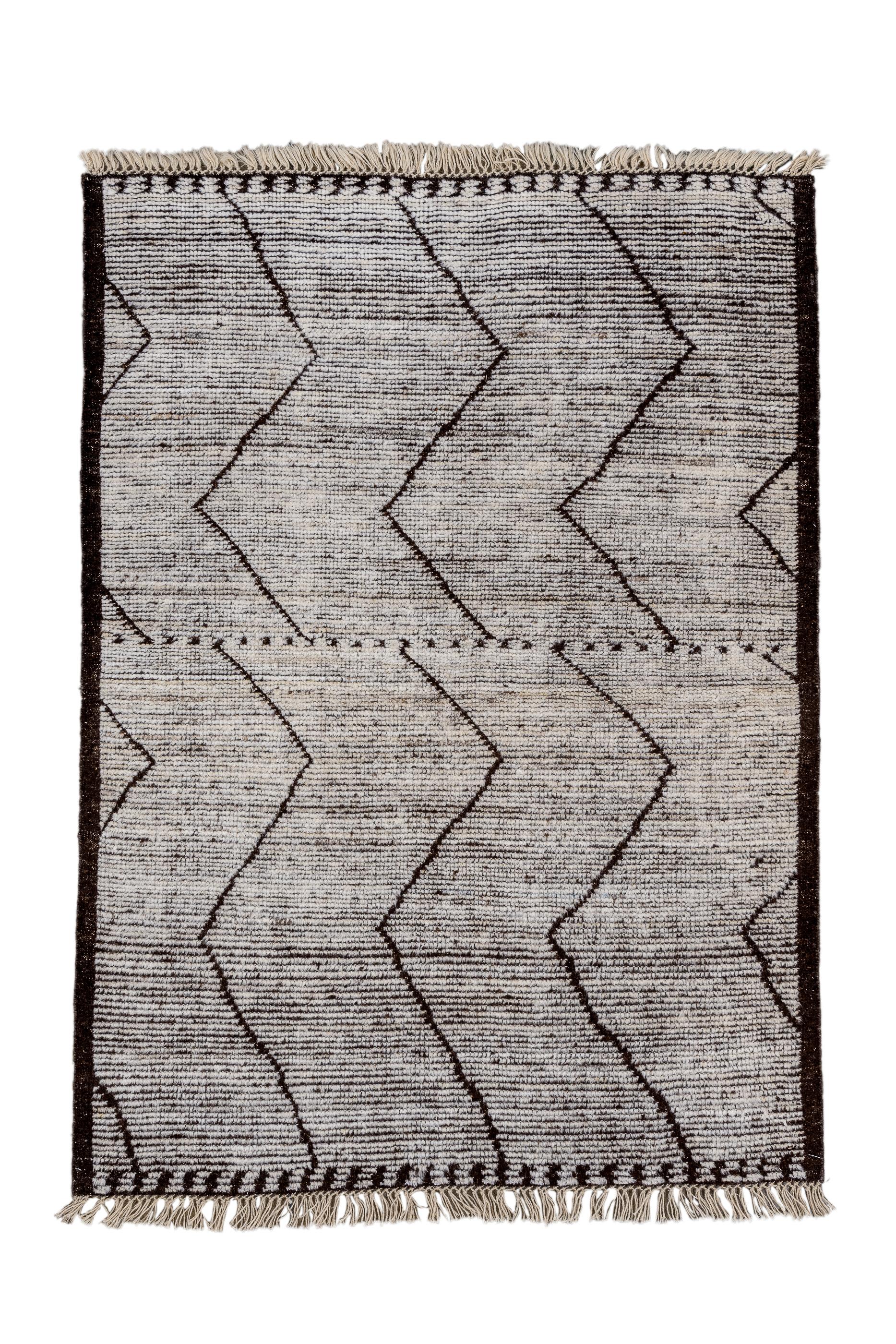 His Turkish village creation shows an abrashed natural beige wool field, decorated by three severed zig-zag verticals, and a few open triangles along the side borders. Dark brown plain string border. Very coarse, with flat, recumbent pile. As new