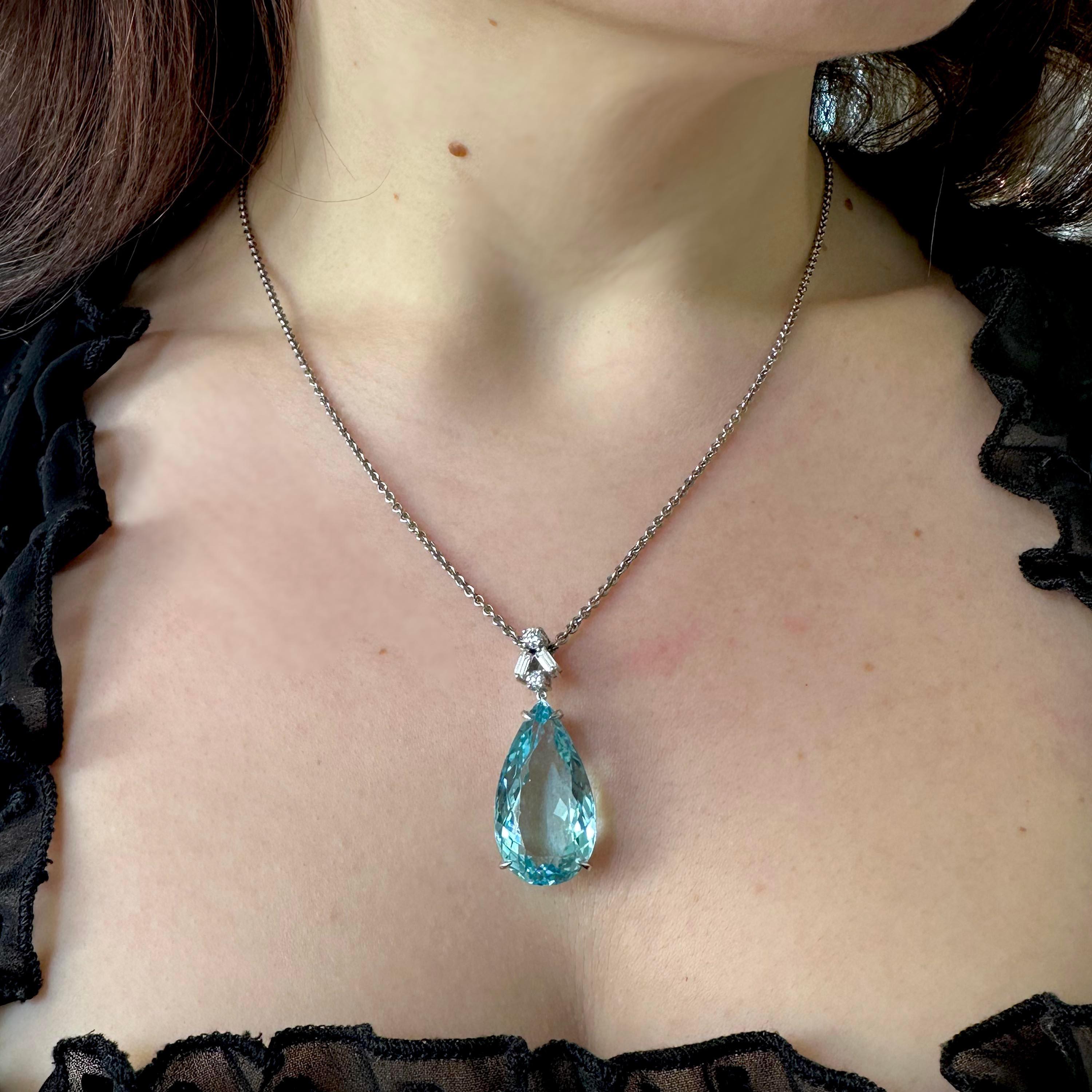 A modern aquamarine and diamond pendant, with a diamond set top section, set with a round brilliant-cut diamond above two baguette-cut diamonds astride a smaller round brilliant-cut diamond, in claw settings, suspending a pear shape aquamarine drop,