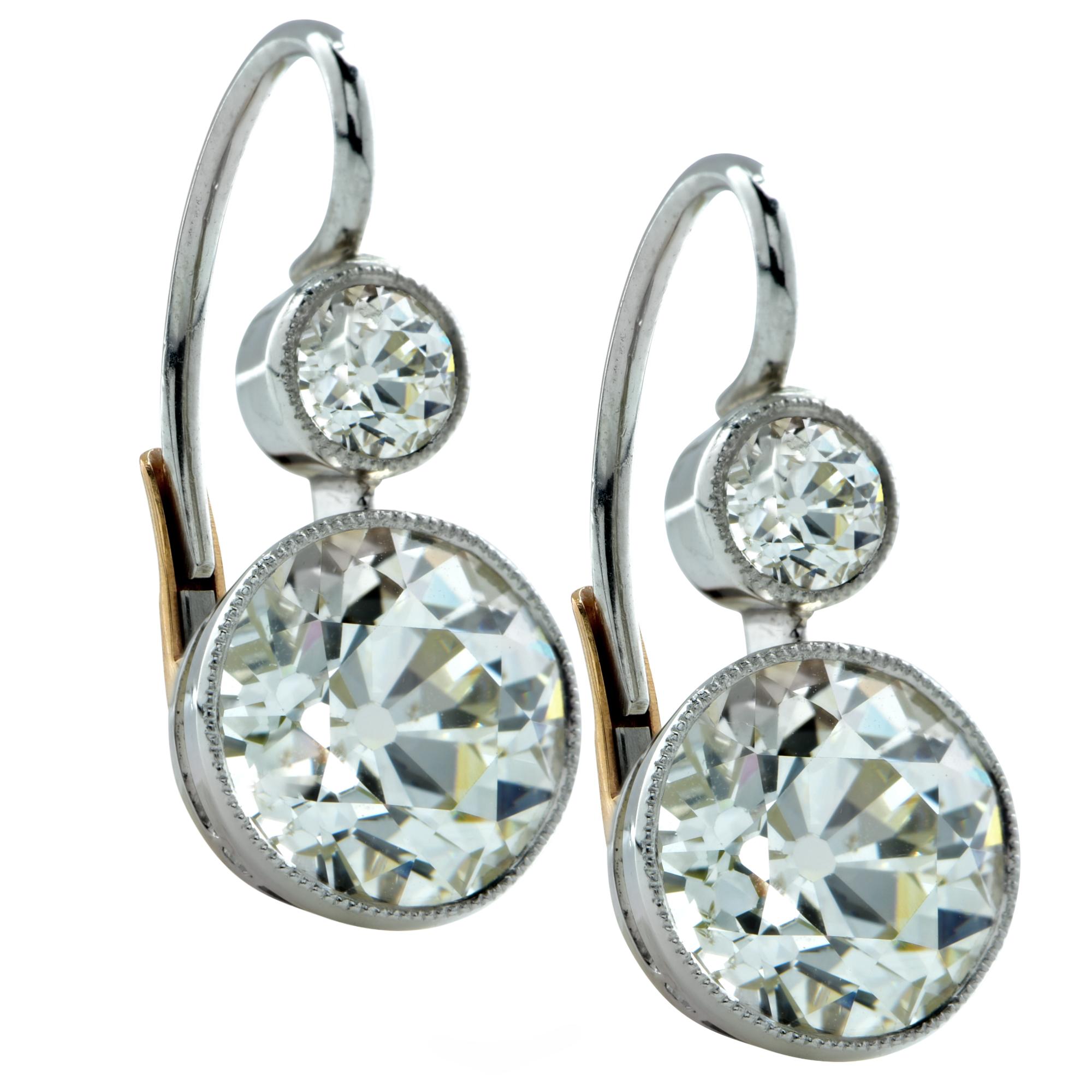 Custom made Art Deco style dangle earrings crafted in platinum featuring 2 Old European cut diamonds weighing 6.17cts total, L-M color VS2-SI1 clarity accented by 2 Old European cut diamonds weighing .50cts total. L color SI clarity framed in