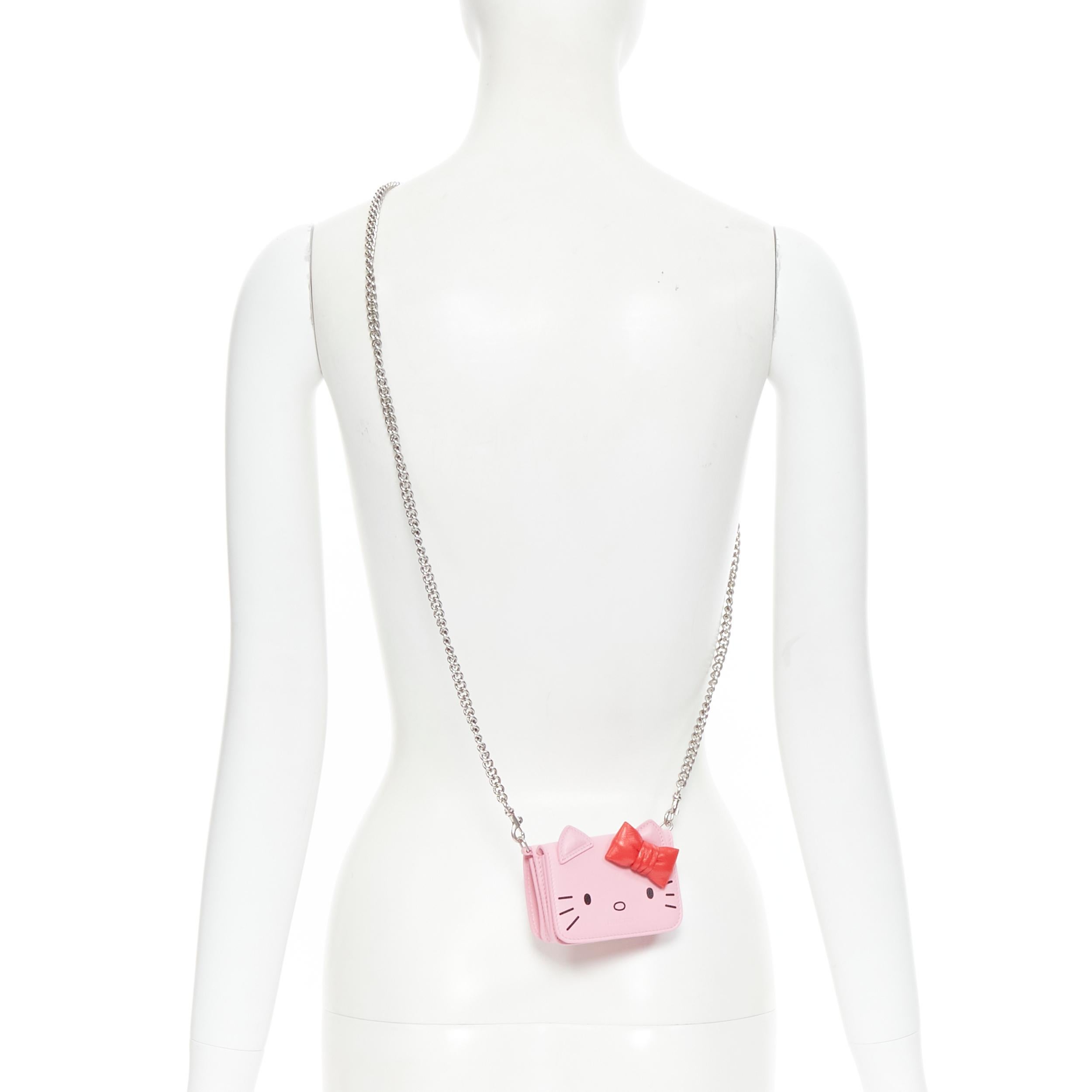 new BALENCIAGA Kitty pink red ribbon wallet micro silver chain crossbody bag 
Reference: TGAS/B01549
Brand: Balenciaga
Designer: Demna Gvasalia
Model: Kitty wallet on chain
Material: Leather
Color: Pink
Pattern: Solid
Closure: Button
Extra Detail:
