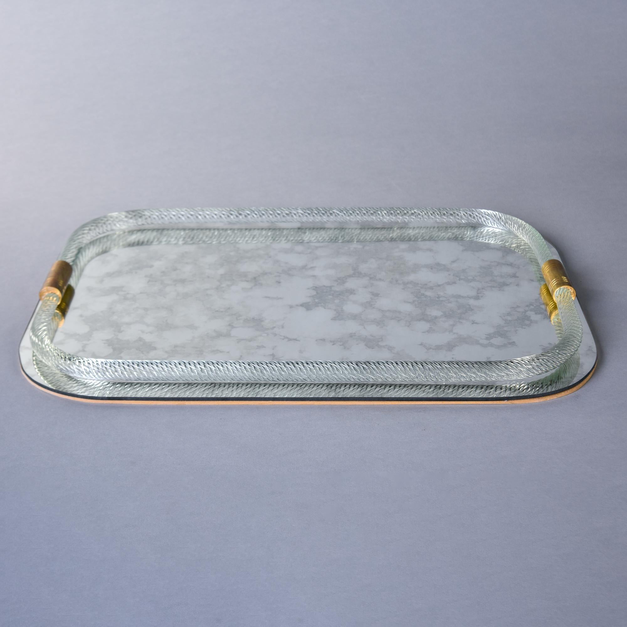 Found in Italy, this mirrored tray with Murano glass border and handles is attributed to Barovier. Rectangular tray has a wooden back with rounded corners, an antiqued mirrored base and a thick, clear twisted mouth blown Murano glass border with