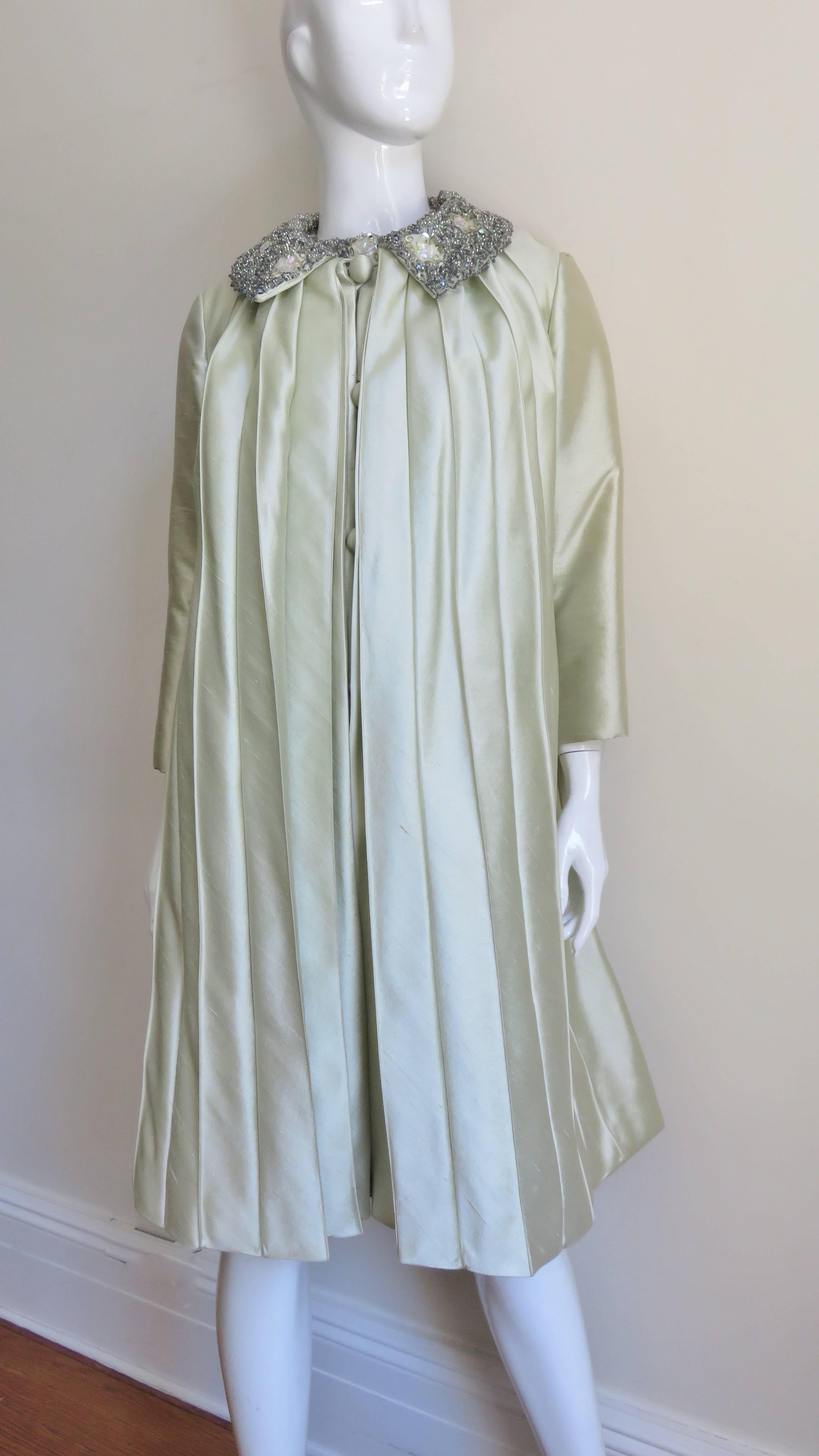 This is a beautiful mint green silk 2 piece dress and coat set. The sleeveless dress is baby doll style with soft folds eminating from the neckline then flaring gently to the hemline.  A 2