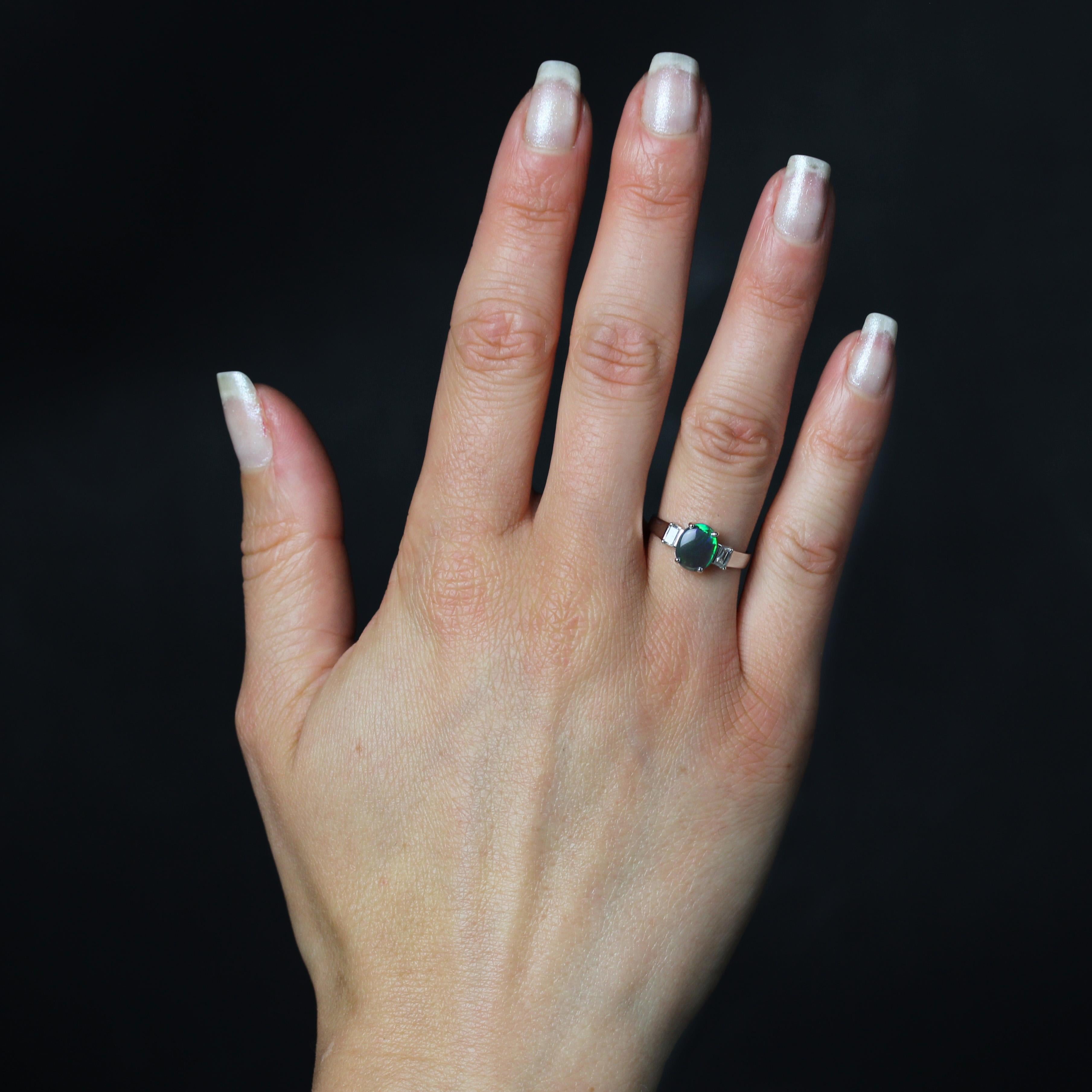 Ring in 18 karat white gold. 
Elegant and sober, this white gold ring is set with 4 claws of a cabochon opal backed on either side by 2 emerald-cut diamonds.
Total weight of the Opal : 0,80 carat approximately.
Total weight of the diamonds : 0,14