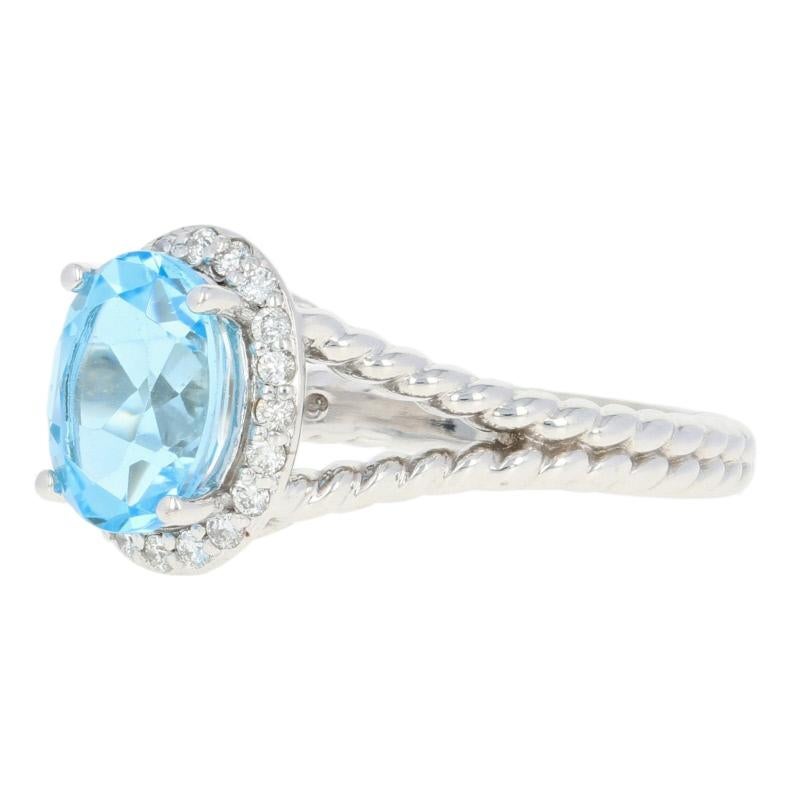 Surprise the special woman in your life with this radiant token of love! Composed of glistening 14k white gold, this NEW ring features a sparkling blue topaz solitaire that is encircled by a luminous white diamond halo which is beautifully accented