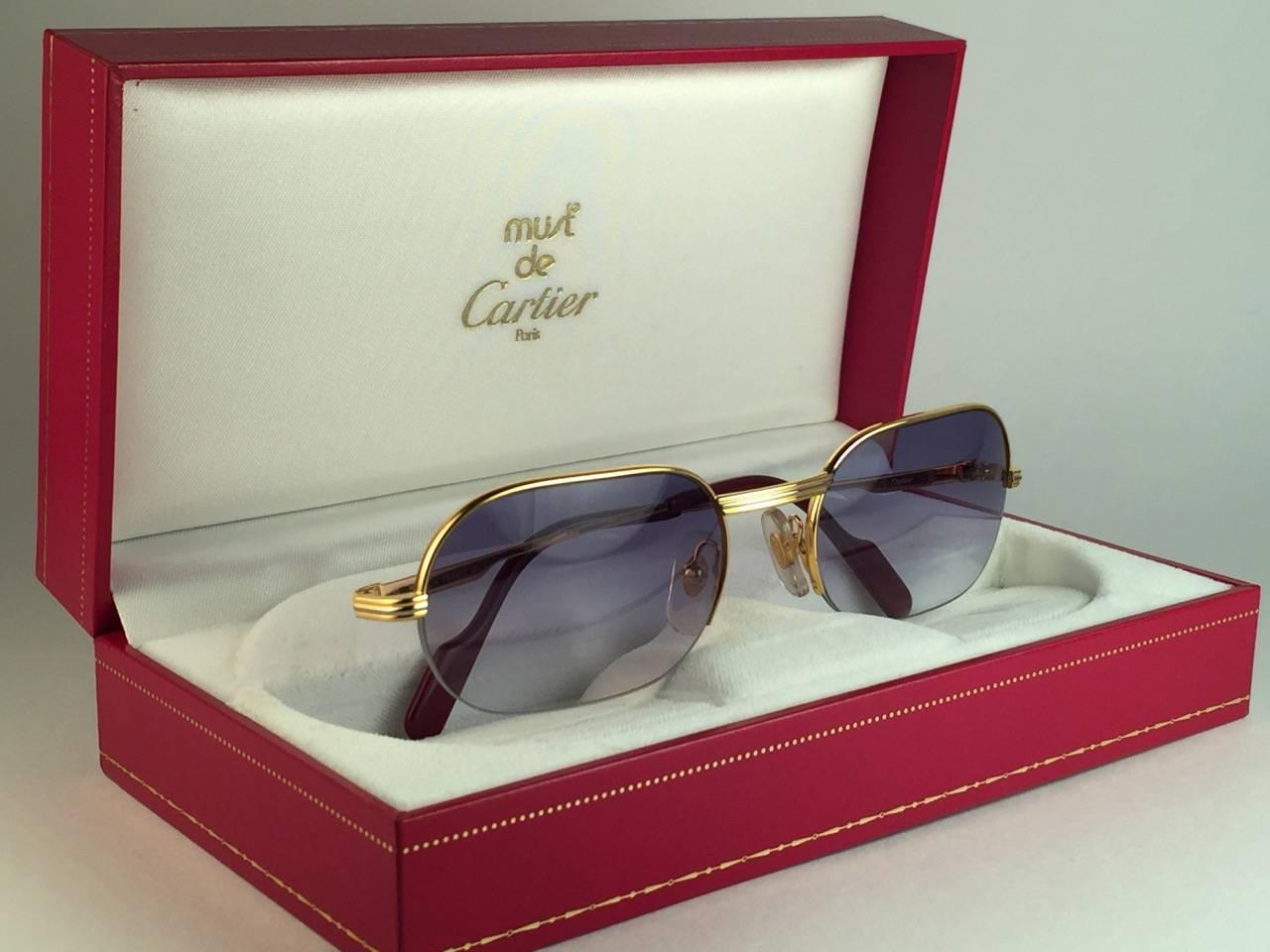 New 1983 Cartier Ascot Vendome Gold 53mm Half Frame with blue gradient (uv protection) lenses. 
Frame is with the front and sides in white and yellow gold heavy 18k plated accents. All hallmarks. Burgundy with Cartier gold signs on the earpaddles.