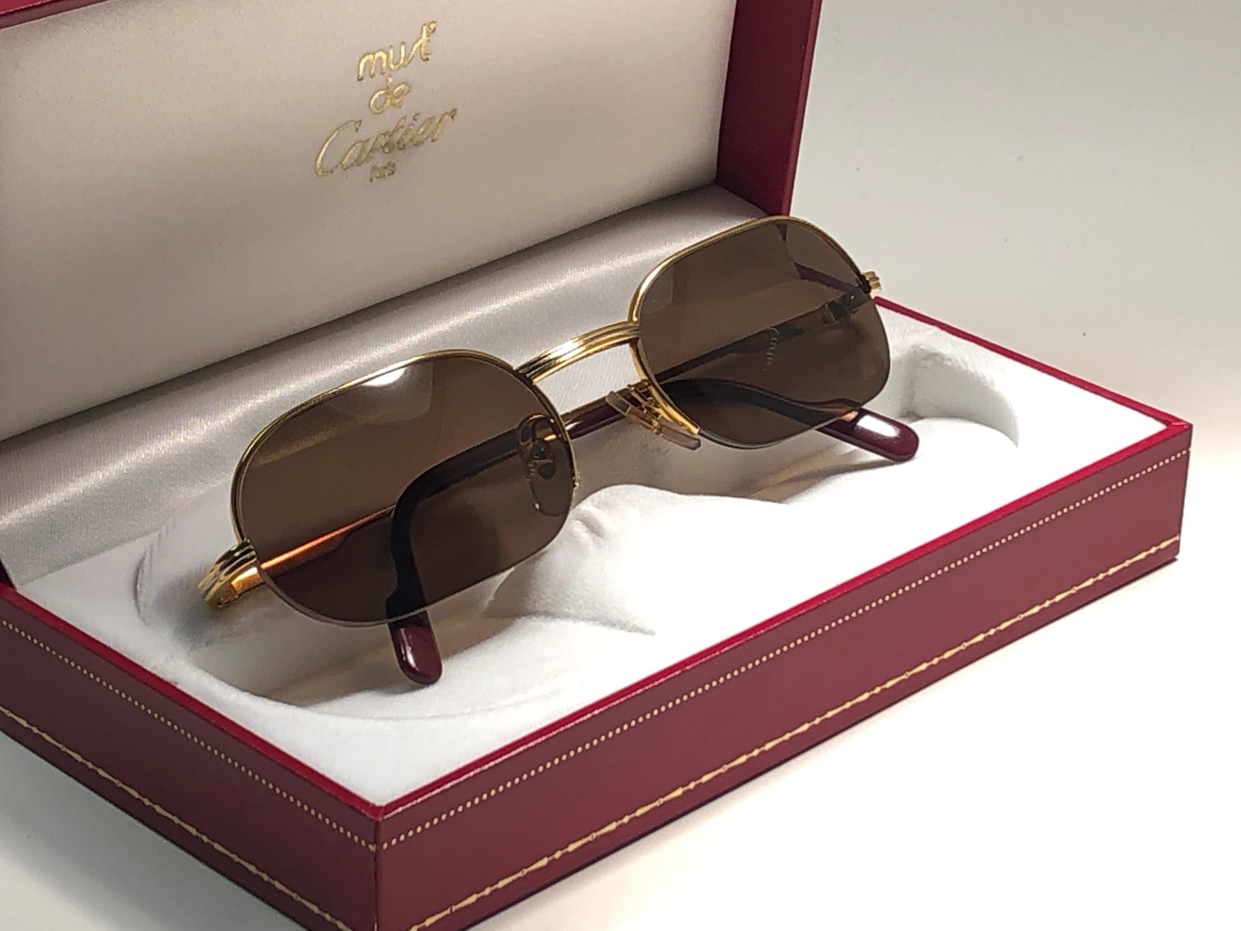 New 1983 Cartier Ascot Vendome Gold 49mm Half Frame with brown (uv protection) lenses. 
Frame is with the front and sides in white and yellow gold heavy 18k plated accents. All hallmarks. Burgundy with Cartier gold signs on the earpaddles. Both arms