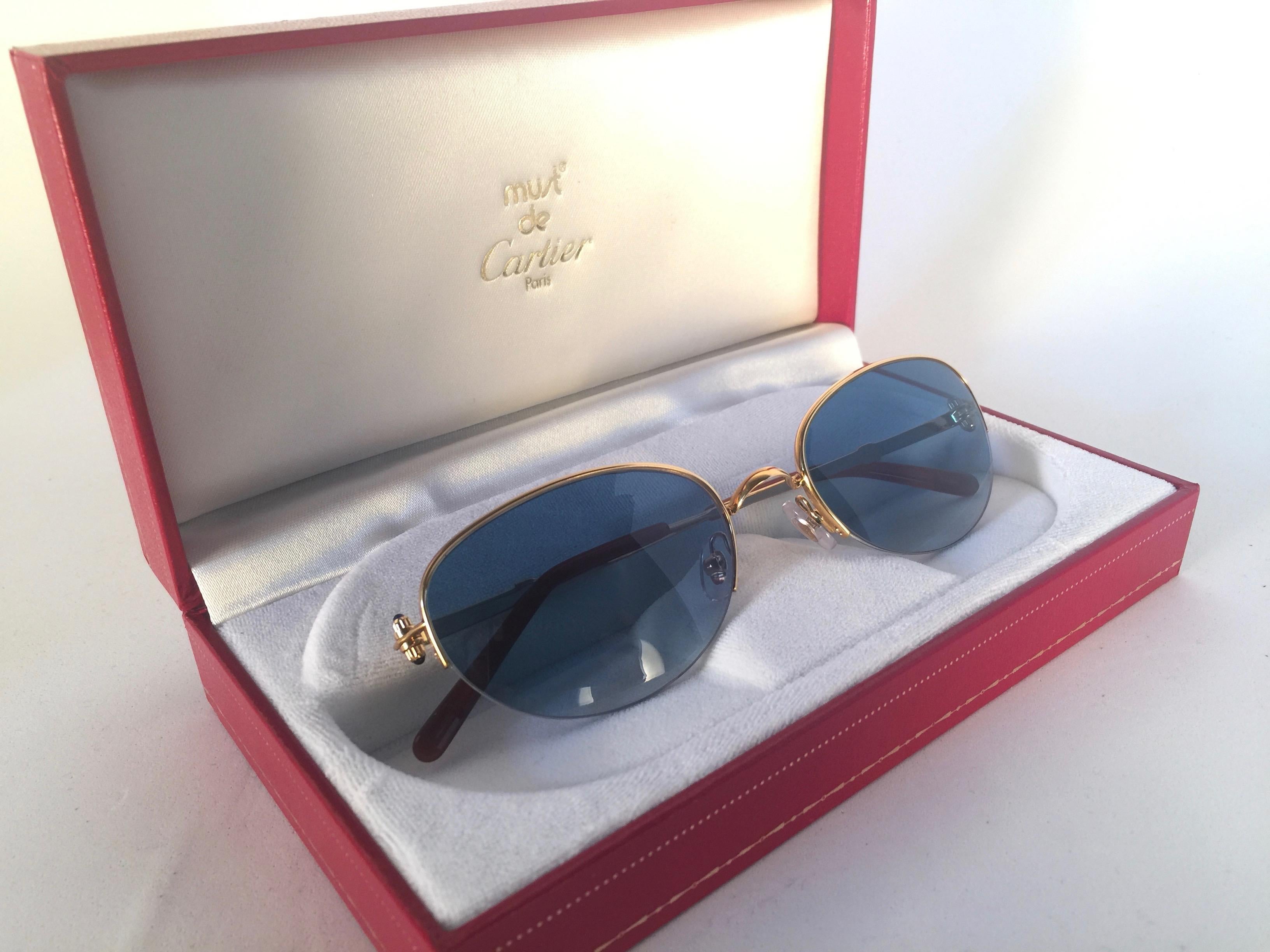 New 1983 Cartier Cabochon Sonnenbrille mit blauen Verlaufsgläsern (UV-Schutz). Der Rahmen ist mit der Vorderseite und den Seiten in Gelb- und Weißgold. Alle Markenzeichen. Cartier-Goldzeichen auf den Ohrpolstern. Mit der Fassung aus 18 Karat Gold