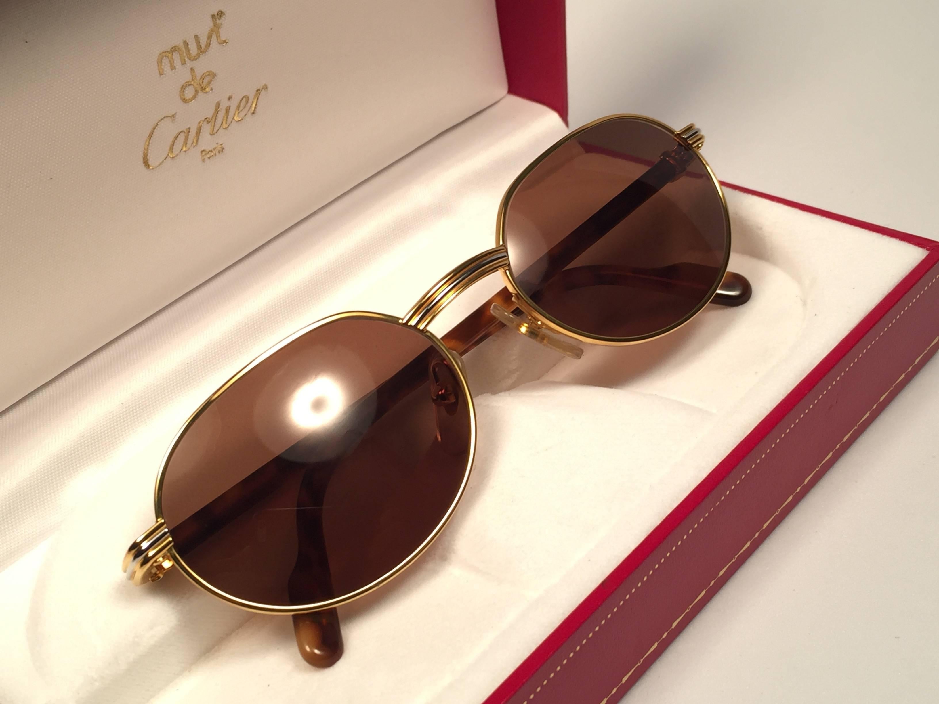 New Cartier oval Lueur sunglasses with spotless brown ( UV protection ) lenses.
All hallmarks. Cartier signs on the ear paddles. 
Both arms sport the knot from Cartier on the temple. These are like a pair of jewels on your nose. 
Beautiful design