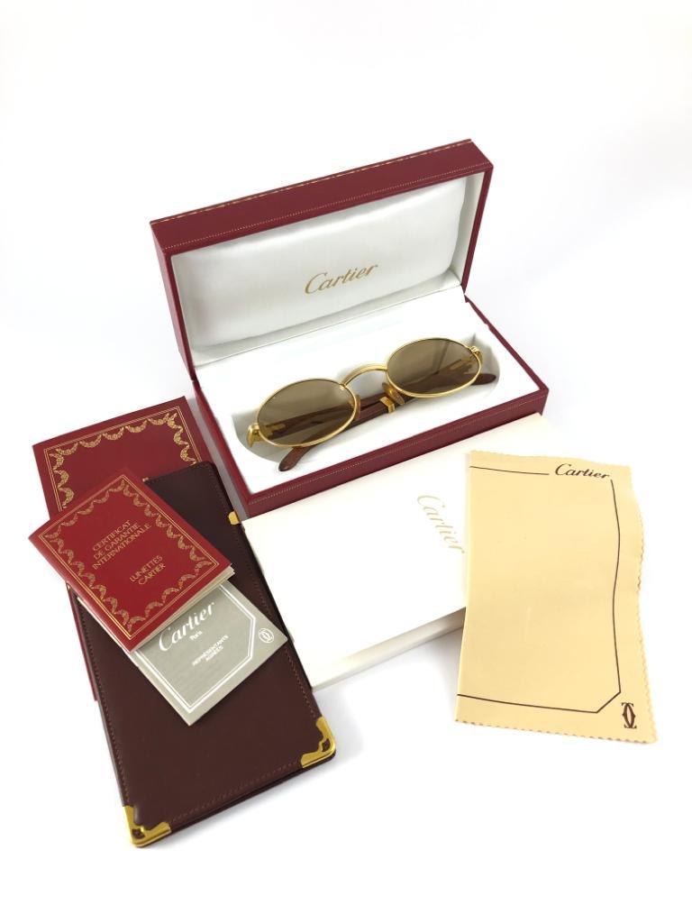 New Original Rare Yellow and White Gold 1992 Cartier classy Giverny Sunglasses with rosewood temples and original Cartier lenses.  
Frame with the front and sides in yellow gold.  
All hallmarks.  Gold Cartier signs on the ear paddles. 
Both arms