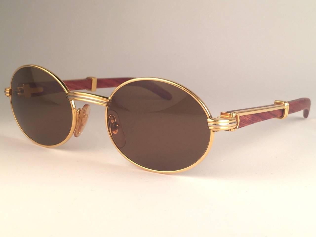 New Original Rare Yellow and White Gold 1992 Cartier classy Giverny Sunglasses with rosewood temples and honey brown spotless uv protection lenses.  
Frame with the front and sides in yellow gold.  
All hallmarks.  Gold Cartier signs on the ear