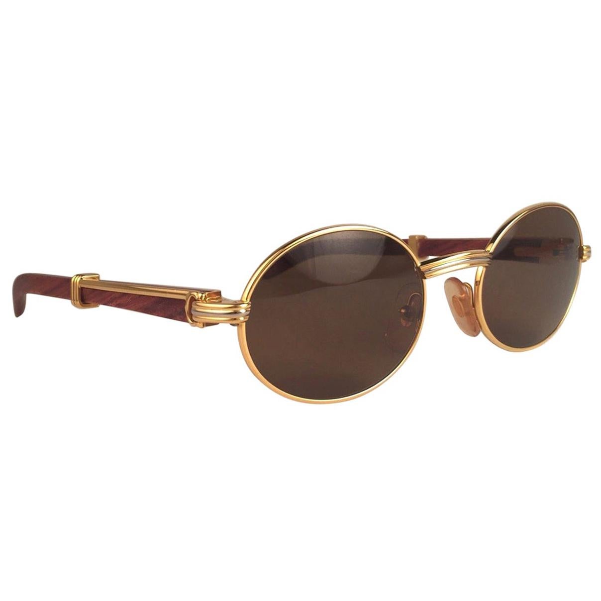 New Original Rare Yellow and White Gold 1992 Cartier classy Giverny Sunglasses with rosewood temples and honey brown spotless uv protection lenses.  
Frame with the front and sides in yellow gold.  
All hallmarks.  Gold Cartier signs on the ear