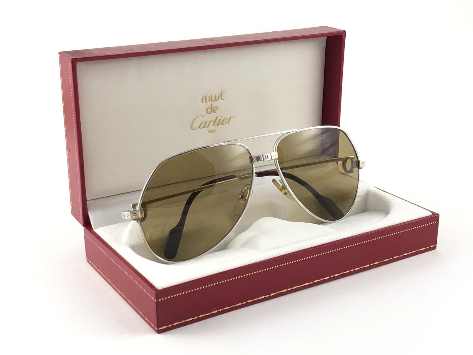 New Cartier Aviator Santos in the ultra rare Platinum plated sunglasses with gold mirror (uv protection) lenses in a Full Cartier Set.
Frame is with the famous Vendome stripes on the front and on the sides.
All hallmarks. Cartier gold signs on the