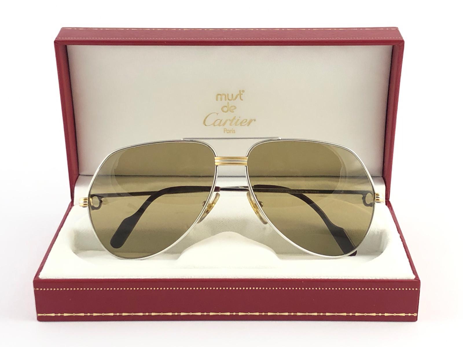 New Cartier Aviator Vendome in the ultra rare Platinum plated sunglasses with gold mirror (uv protection) lenses in a Full Cartier Set.
Frame is with the famous Vendome stripes on the front and on the sides.
All hallmarks. Honey brown enamel with