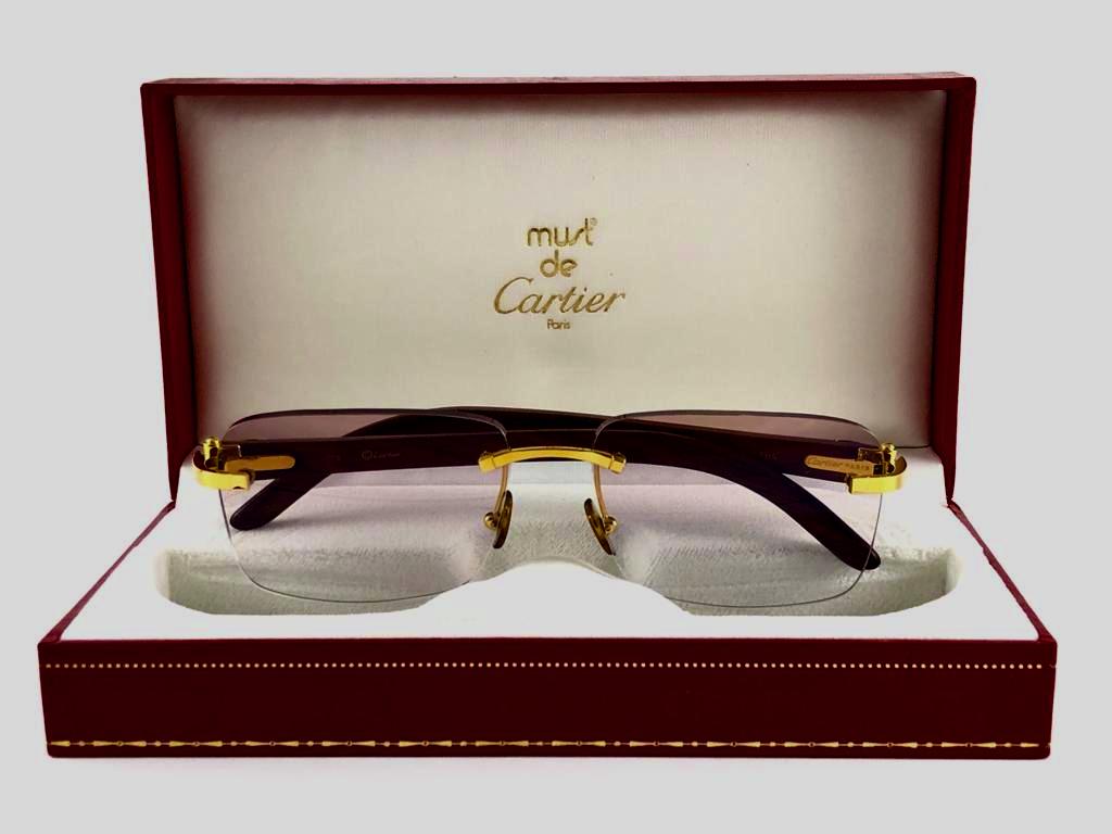 Vintage Original Cartier Sunglasses with C Monogram carved wood temples and light rose gradient uv protection lenses.  
Frame with the front and sides in gold.  
All hallmarks. Cartier signs on the ear paddles. 
Both arms sport the c from Cartier on