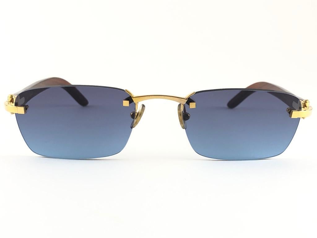 Vintage Original Cartier Sunglasses with wood temples and blue gradient uv protection lenses.  
Frame with the front and sides in gold.  
All hallmarks. Cartier signs on the ear paddles. 
Both arms sport the c from Cartier on the temple.  These are