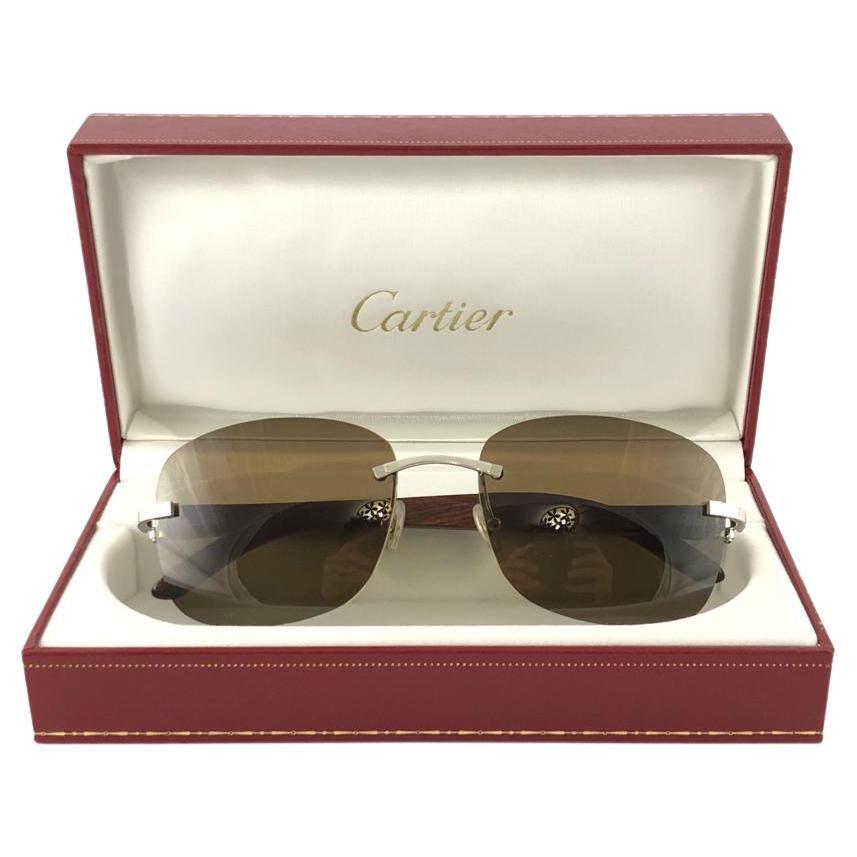 Vintage Original Cartier Sunglasses with monogram wood temples and brown uv protection lenses.  
Frame with the front and sides in platine.  
All hallmarks. Cartier signs on the ear paddles. 
Both arms sport the c from Cartier on the temple.  These