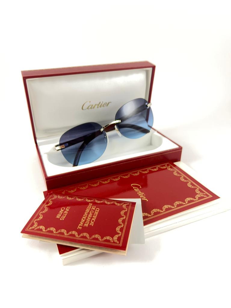 Vintage Original Cartier Sunglasses with wood temples and blue gradient uv protection lenses.  
Frame with the front and sides in platine plated C Decor.

All hallmarks. Cartier signs on the ear paddles. 
Both arms sport the c from Cartier on the