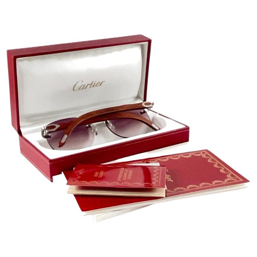 Vintage Original Cartier Sunglasses with wood temples and mauve gradient uv protection lenses.  
Frame with the front and sides in platine plated C Decor.

All hallmarks. Cartier signs on the ear paddles. 
Both arms sport the c from Cartier on the