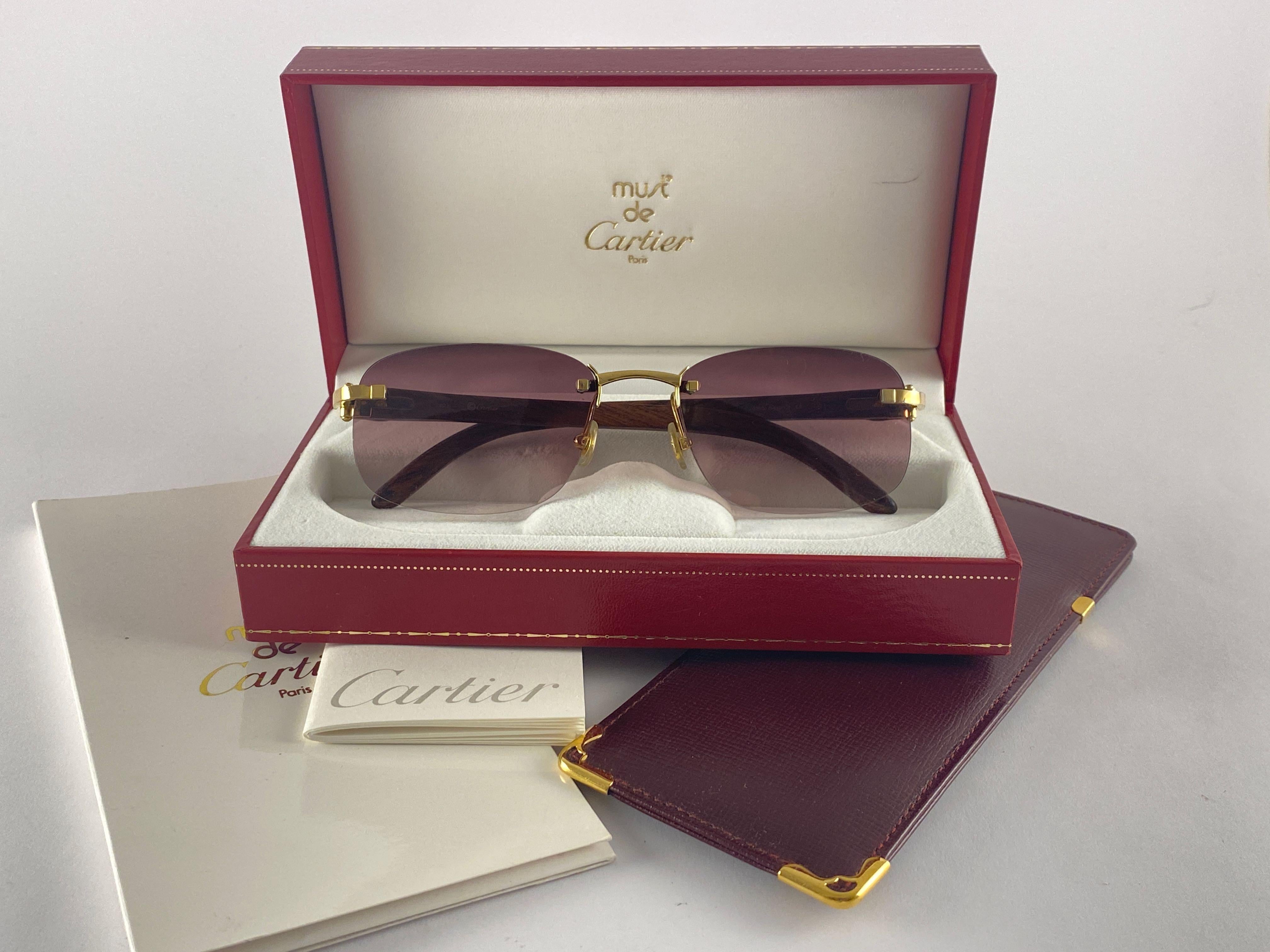 Vintage Original Cartier Sunglasses with wood temples and mauve gradient uv protection lenses.  
Frame with the front and sides in gold plated.  
All hallmarks. Cartier signs on the ear paddles. 
Both arms sport the c from Cartier on the temple. 