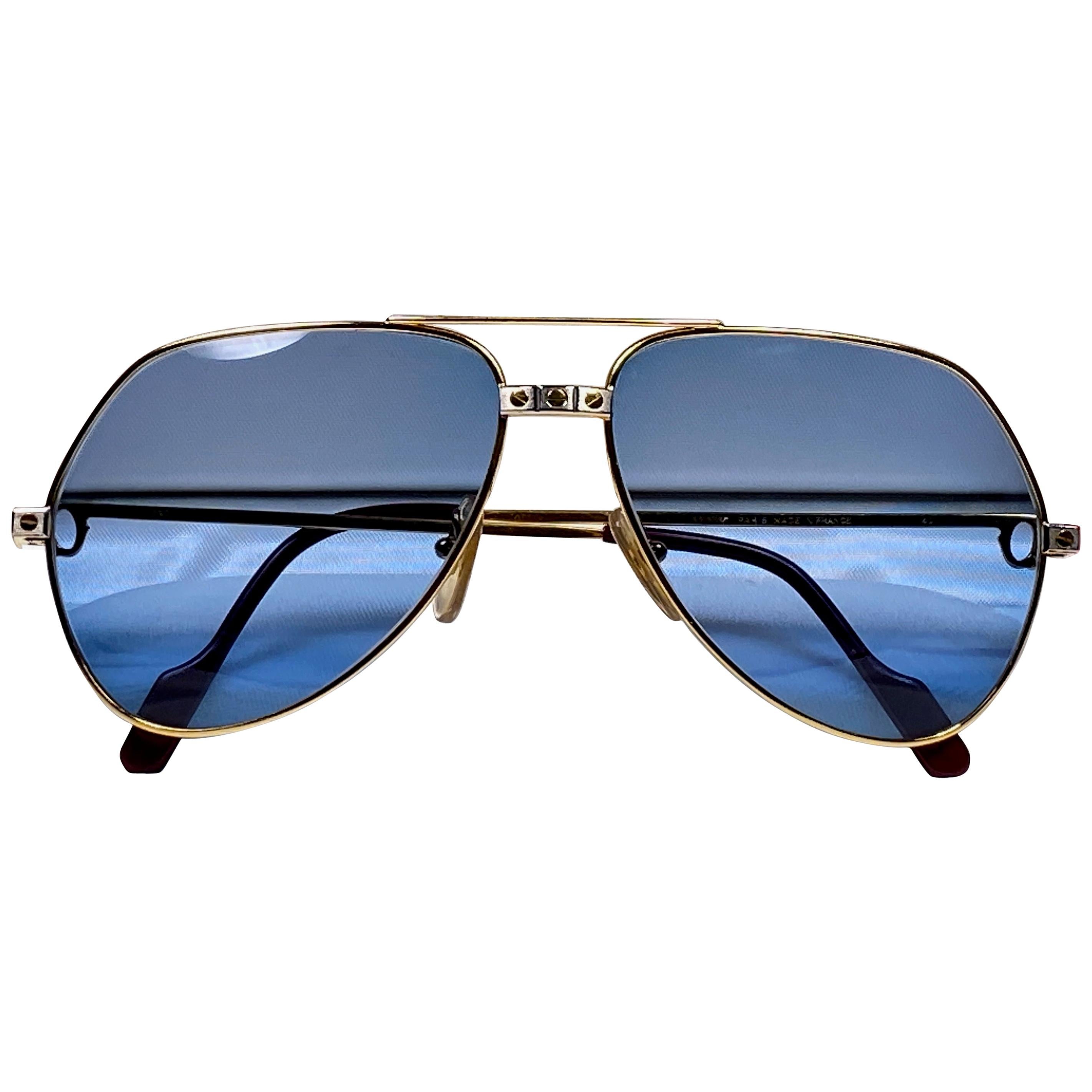 New from 1983!!! Cartier Aviator Santos Sunglasses with blue (uv protection) Lenses. Frame is with the famous screws on the front and sides in yellow and white gold. All hallmarks. Red enamel with Cartier gold signs on the ear paddles. Both arms