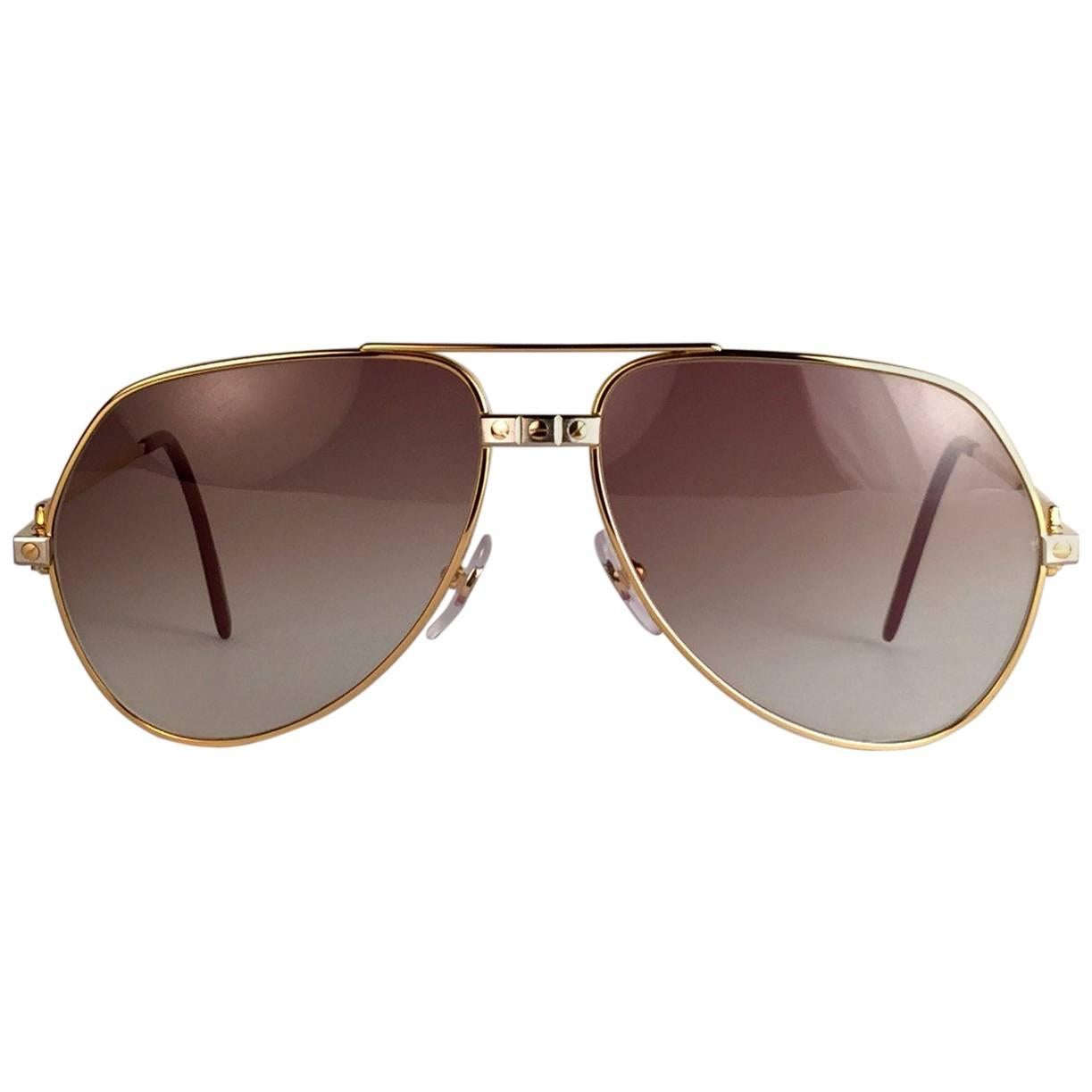 New from 1983!!! Cartier Aviator Santos Sunglasses with Brown Gradient (uv protection) Lenses. 
Frame is with the famous screws on the front and sides in yellow and white gold. All hallmarks. Red enamel with Cartier gold signs on the ear paddles.